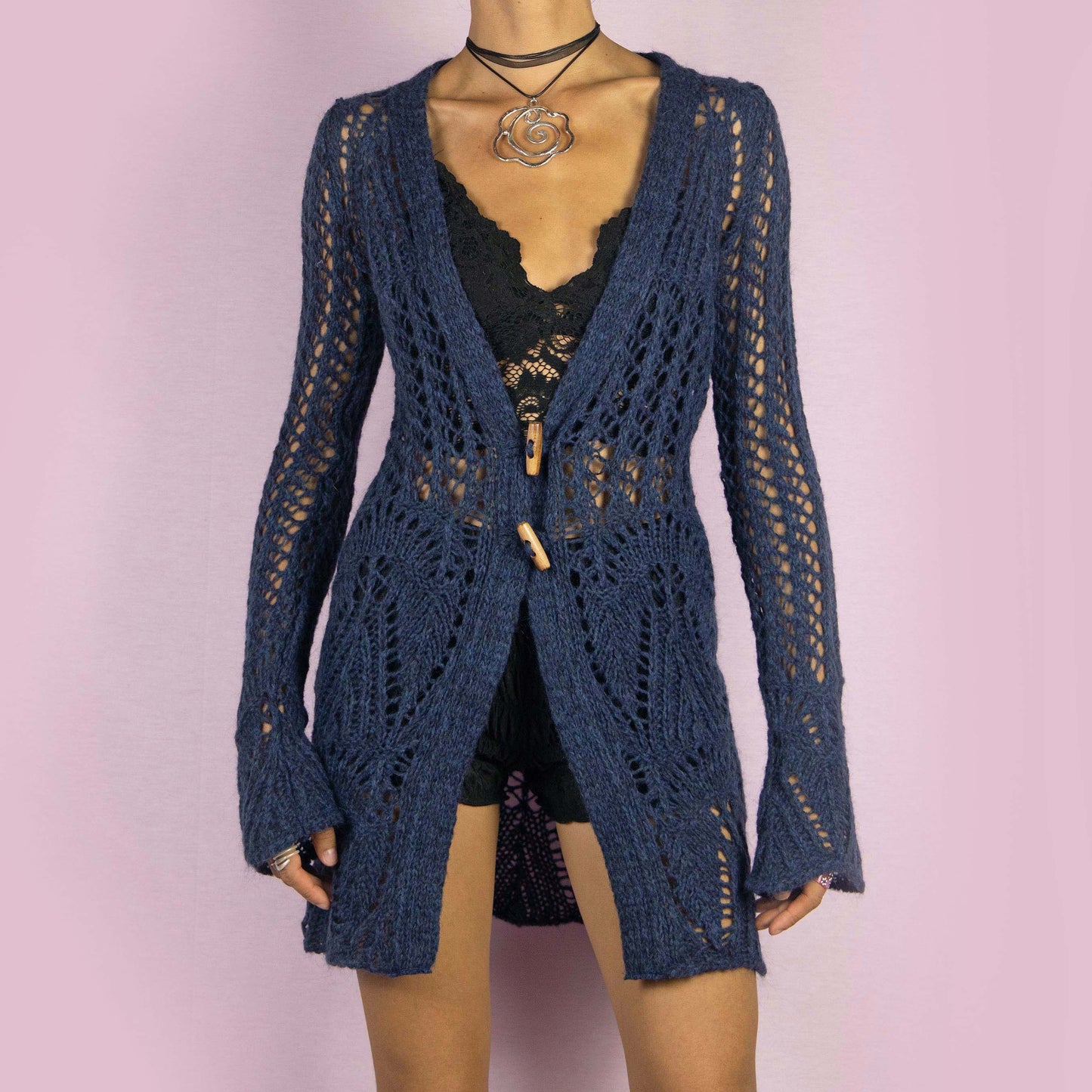 The Y2K Blue Long Crochet Cardigan is a vintage 2000s cardigan featuring a deep V-neckline and long, flared sleeves. Made from a wool blend, this longline cardigan is lightweight yet cozy, with wooden toggle button closures and a stretchy design. Perfect for layering over outfits in cooler weather.