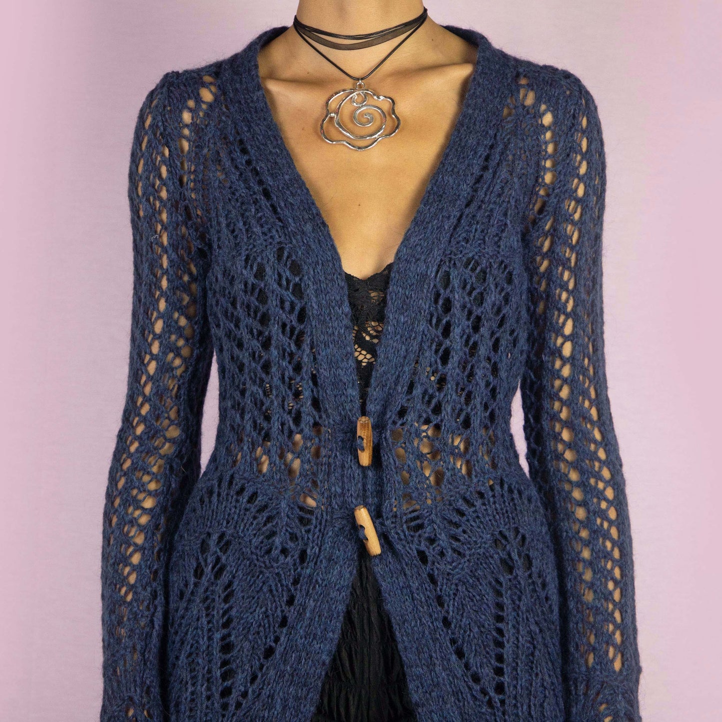 The Y2K Blue Long Crochet Cardigan is a vintage 2000s cardigan featuring a deep V-neckline and long, flared sleeves. Made from a wool blend, this longline cardigan is lightweight yet cozy, with wooden toggle button closures and a stretchy design. Perfect for layering over outfits in cooler weather.
