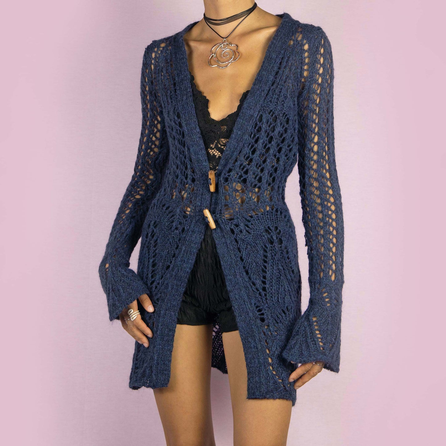 The Y2K Blue Long Crochet Cardigan is a vintage 2000s cardigan featuring a deep V-neckline and long, flared sleeves. Made from a wool blend, this longline cardigan is lightweight yet cozy, with wooden toggle button closures and a stretchy design. Perfect for layering over outfits in cooler weather.