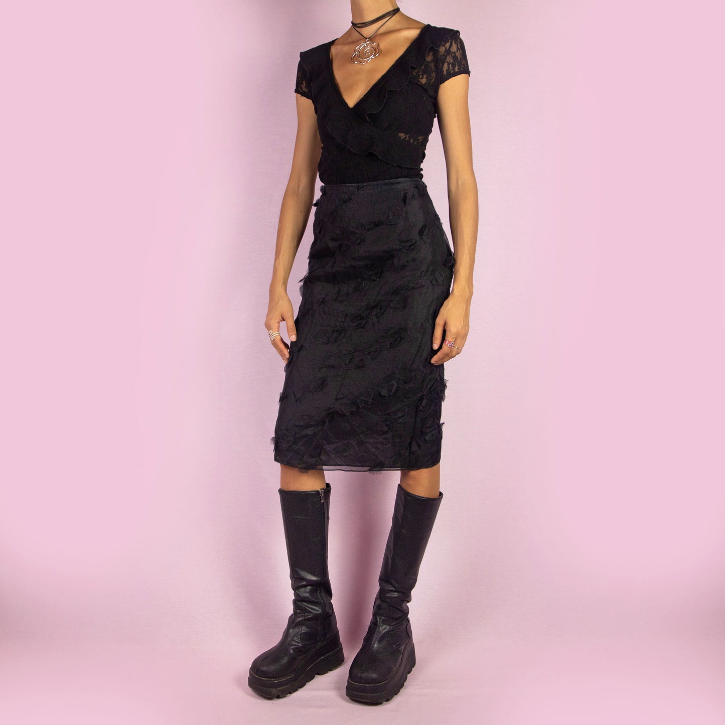 The Y2K Black Applique Midi Skirt is a vintage 2000s piece featuring intricate appliqué details throughout. This elegant skirt has a side zipper closure and a flattering high-waisted fit. It is semi-sheer, making it perfect for special occasions.