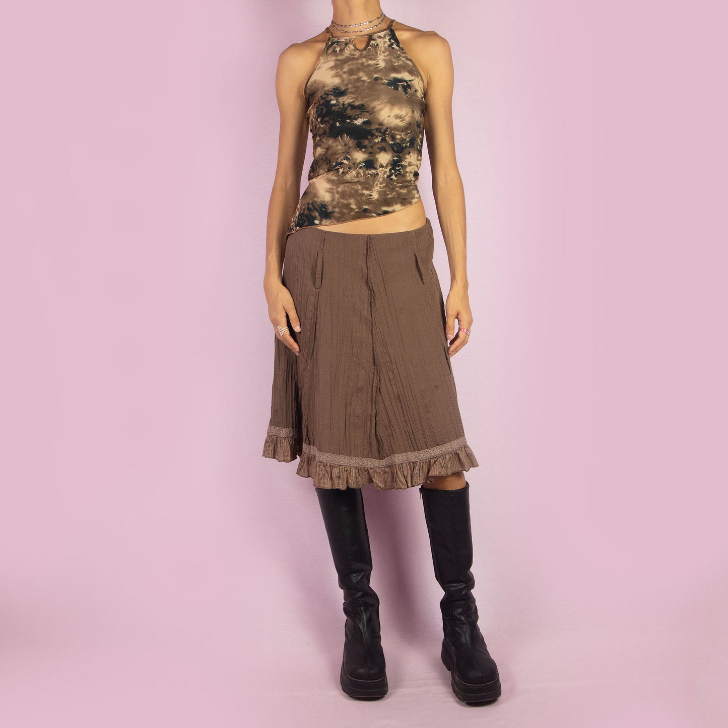 The Y2K Brown Flared Skirt is a vintage 2000s high-waisted skirt featuring a side zipper closure, a crinkled fabric texture, and delicate lace trim along the hemline with ruffle detailing. Perfect for casual or summer looks.