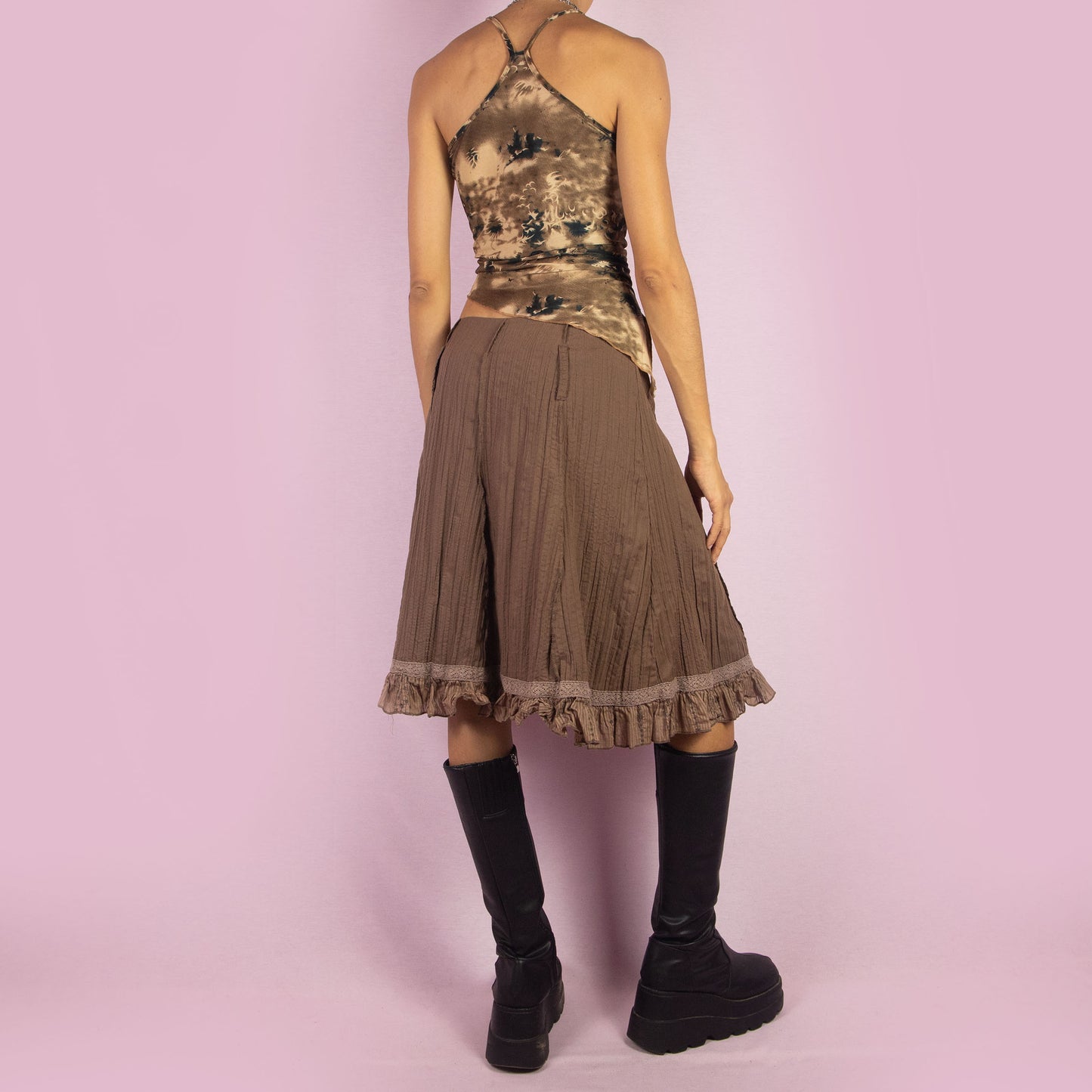 The Y2K Brown Flared Skirt is a vintage 2000s high-waisted skirt featuring a side zipper closure, a crinkled fabric texture, and delicate lace trim along the hemline with ruffle detailing. Perfect for casual or summer looks.