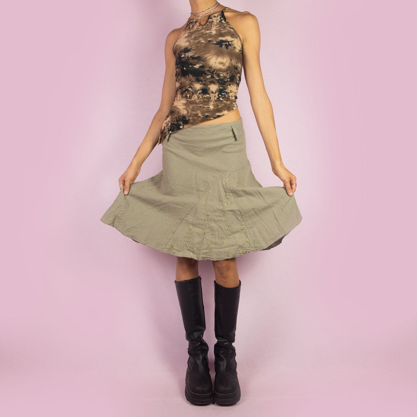 The Y2K Khaki Flared Trumpet Skirt is a vintage 2000s midi skirt crafted from a lightweight linen-cotton blend. It features a high-waisted fit with a side zipper closure, complemented by a flared trumpet silhouette with subtle embroidery details. Perfect for casual, boho-inspired summer and spring outfits.