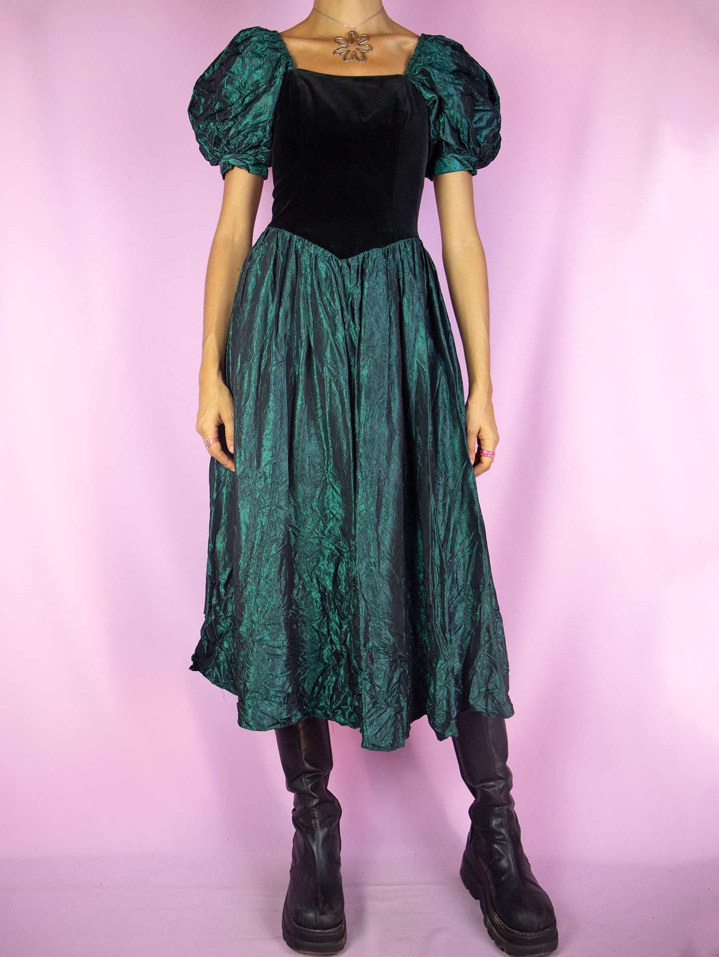 The Vintage 90s Puff Sleeve Midi Dress is a stunning piece featuring a square neckline, voluminous puff sleeves, and a fitted velvet bodice with a back zipper closure. The dress flows into a gathered skirt made of crinkled emerald green fabric, creating an elegant contrast. Perfect for formal occasions and evening events.