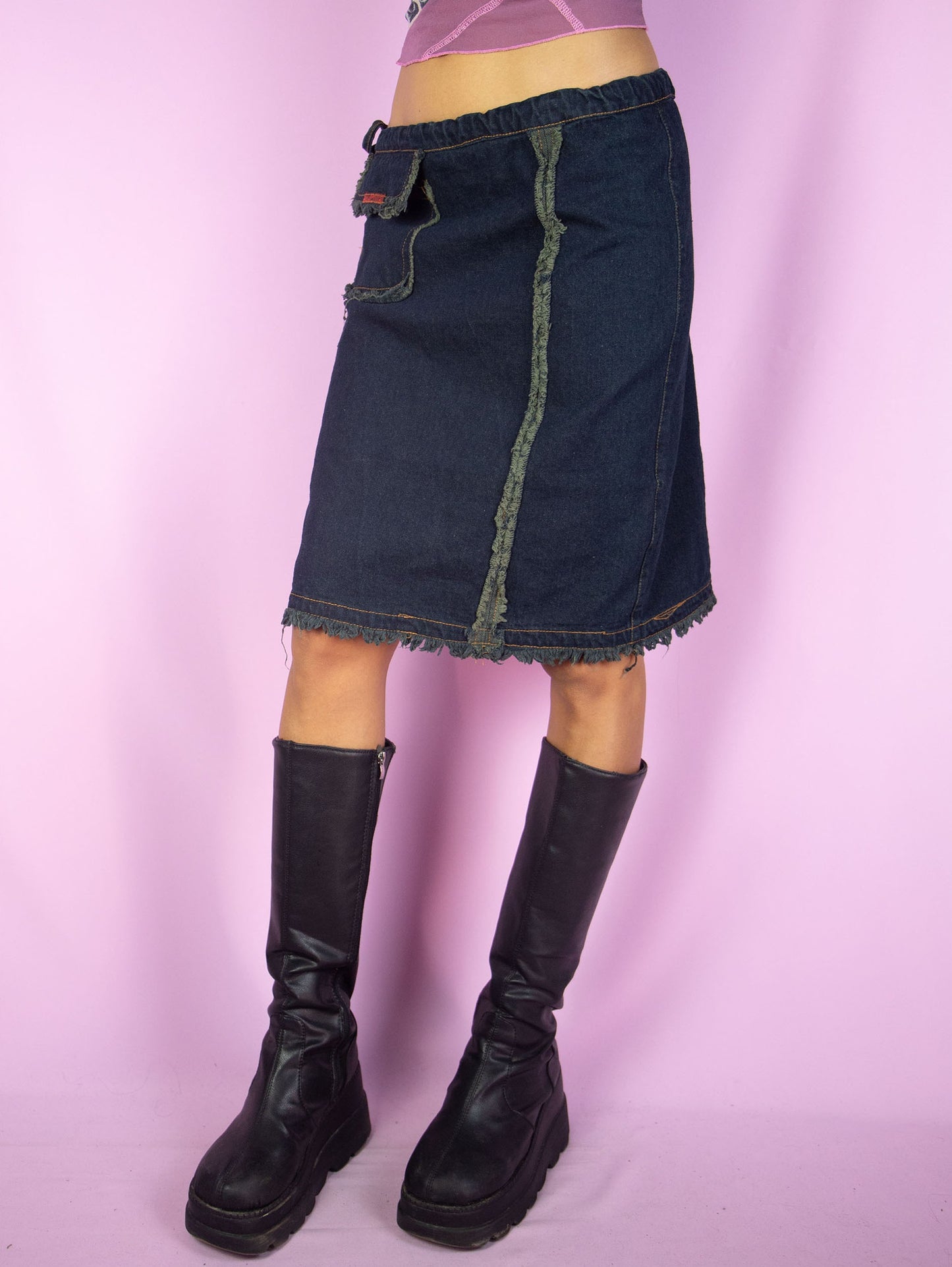 The Y2K Asymmetric Denim Mini Skirt is a vintage dark denim navy blue skirt tied at the side with a pocket and frayed seam details. Cyber goth grunge 2000s subversive gorpcore jean skirt.