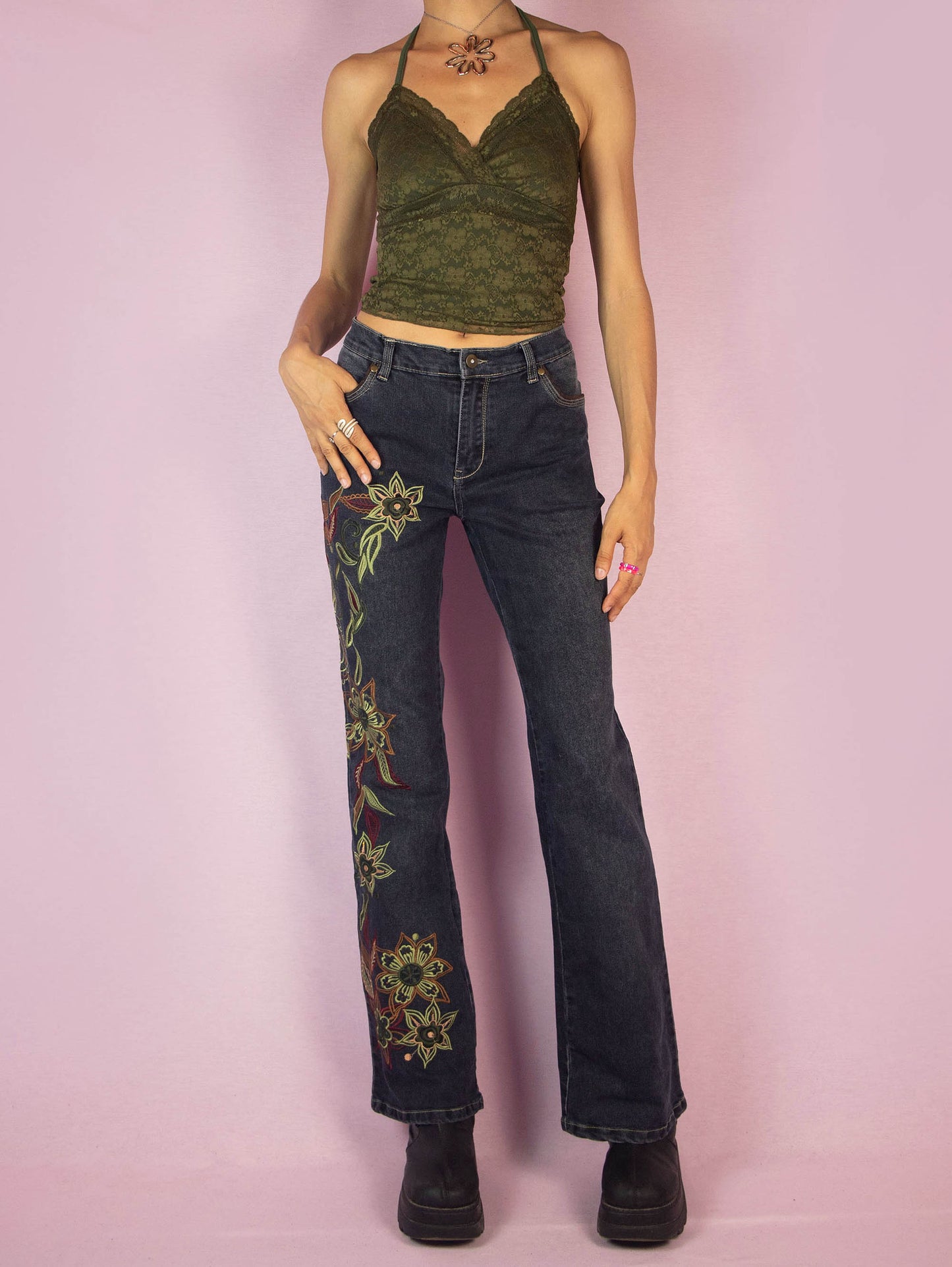 The Y2K Floral Embroidered Jeans are a vintage 2000s piece featuring floral embroidery along the leg, a mid-rise fit, stretchy dark denim, straight leg cut, front and back pockets, and a zipper closure. These jeans add a unique, bohemian flair to your casual or festival outfits.