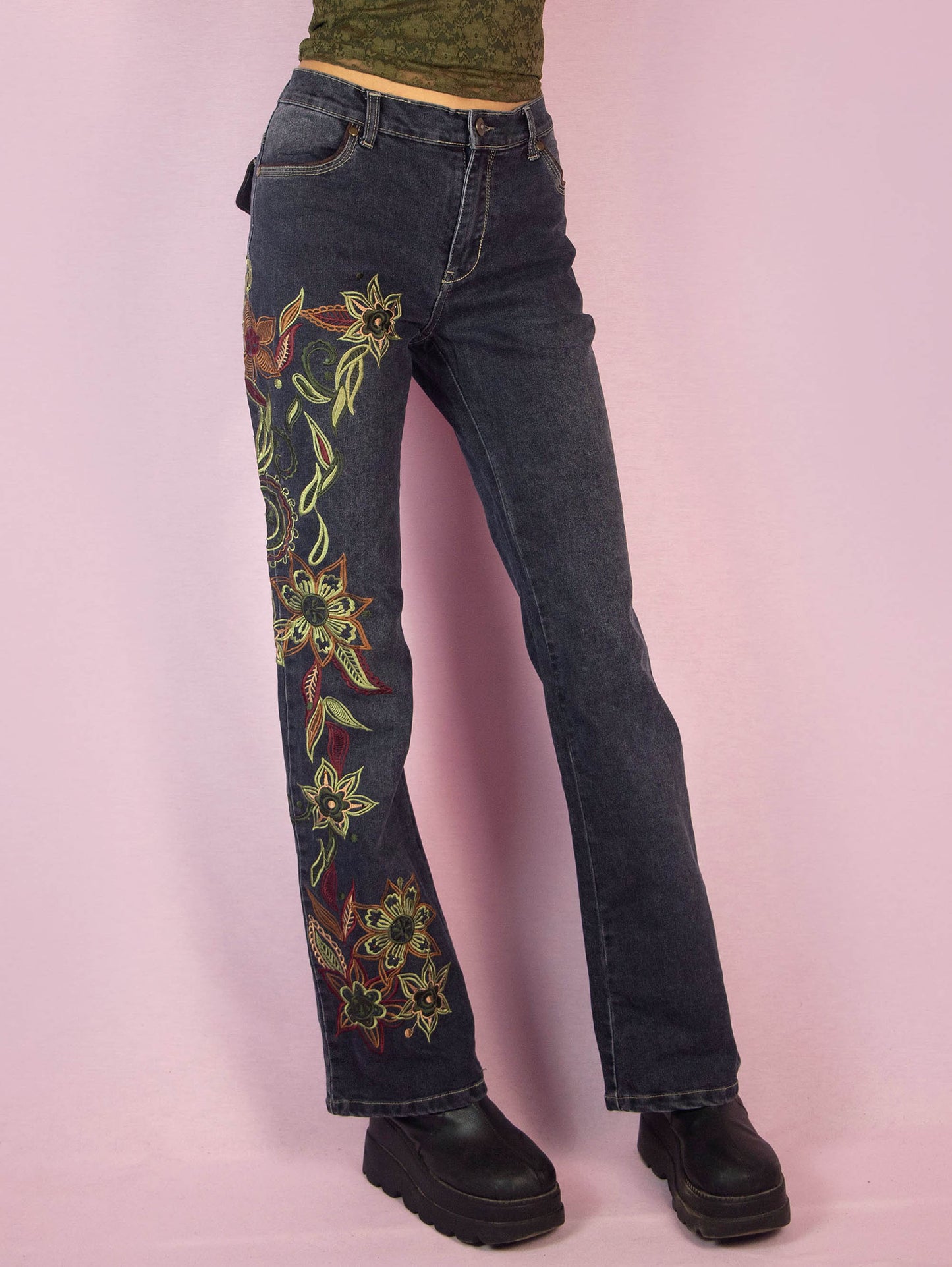 The Y2K Floral Embroidered Jeans are a vintage 2000s piece featuring floral embroidery along the leg, a mid-rise fit, stretchy dark denim, straight leg cut, front and back pockets, and a zipper closure. These jeans add a unique, bohemian flair to your casual or festival outfits.