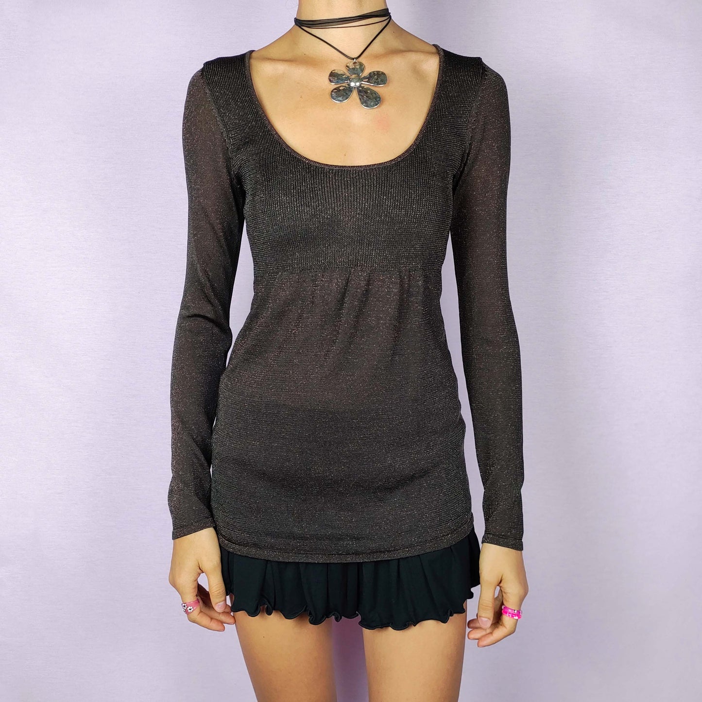 The Y2K Brown Sparkle Knit Top is a vintage 2000s piece, featuring a metallic thread woven throughout for a subtle shimmer, a scoop neckline and long sleeves, and is designed in a peplum style. Ideal for a night out or any autumn outfit.