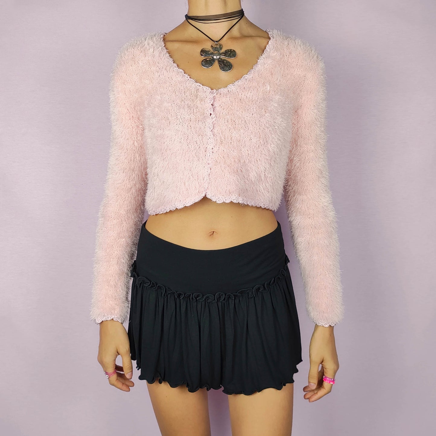 The Vintage 90s Pink Cropped Cardigan is a cozy, fuzzy knit piece that adds a soft and romantic touch to any outfit. This delicate cardigan features a cropped silhouette, a button closure and a fluffy texture in a pastel pink shade. Ideal for a cute and comfy look.