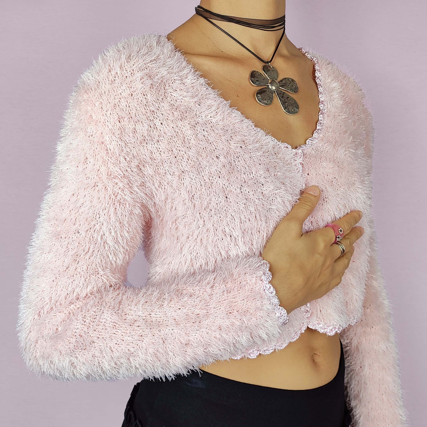 The Vintage 90s Pink Cropped Cardigan is a cozy, fuzzy knit piece that adds a soft and romantic touch to any outfit. This delicate cardigan features a cropped silhouette, a button closure and a fluffy texture in a pastel pink shade. Ideal for a cute and comfy look.
