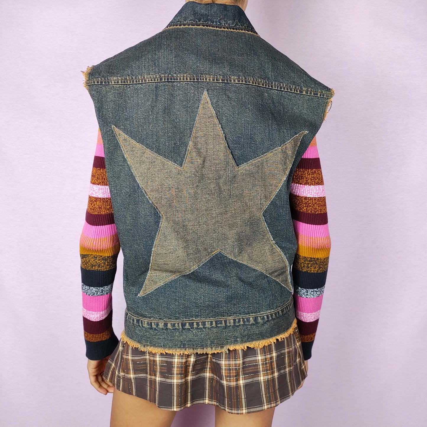 The Y2K Sleeveless Denim Vest Jacket is a vintage 2000s piece featuring a star patch on the back and a button-up front closure. The raw, frayed edges give it a distressed look. Perfect for layering in casual autumn outfits.