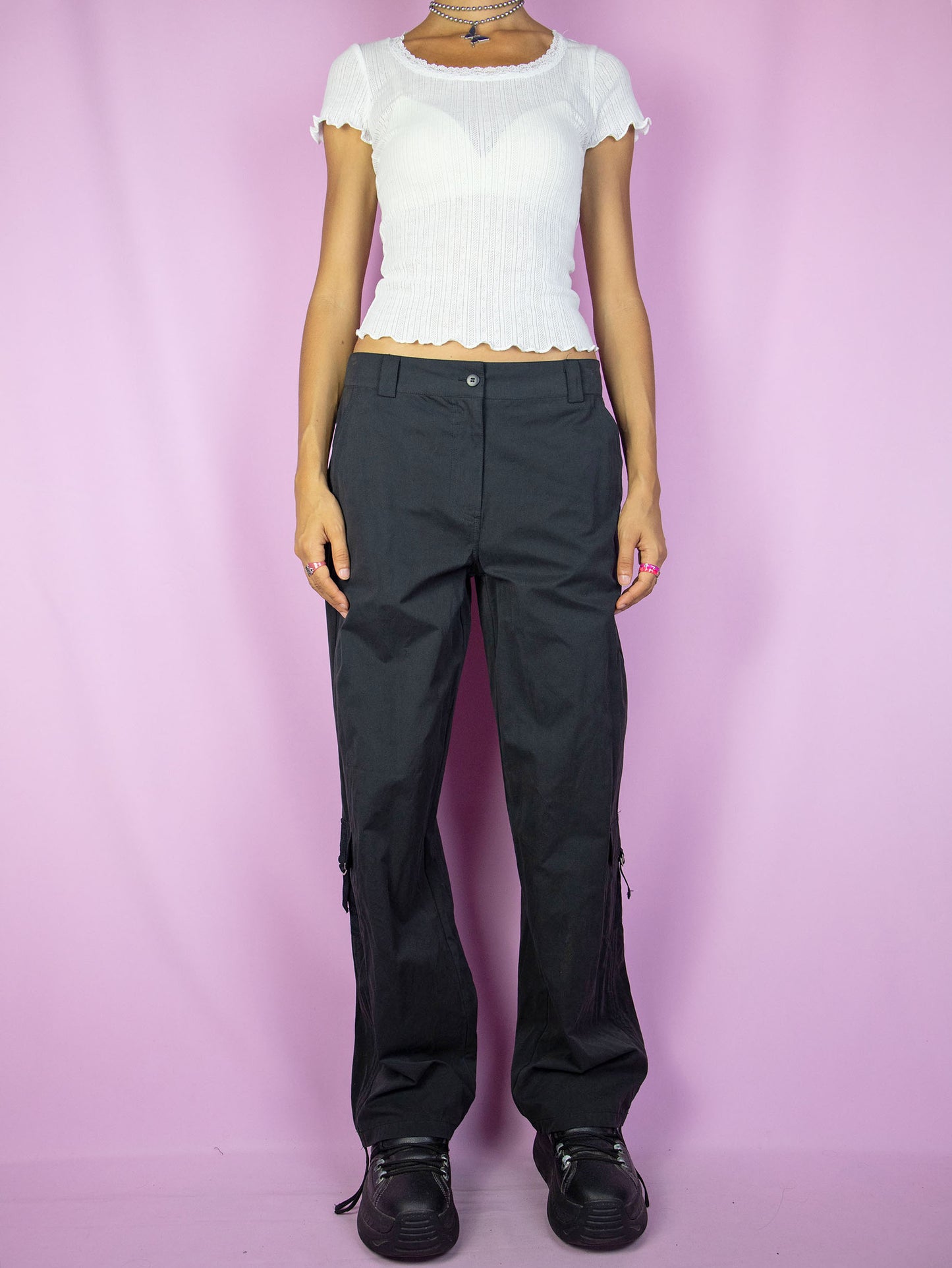 The Y2K Black Cargo Pants are vintage mid-rise wide pants with pockets and a front zipper closure. Cyber grunge 2000s utility trousers.