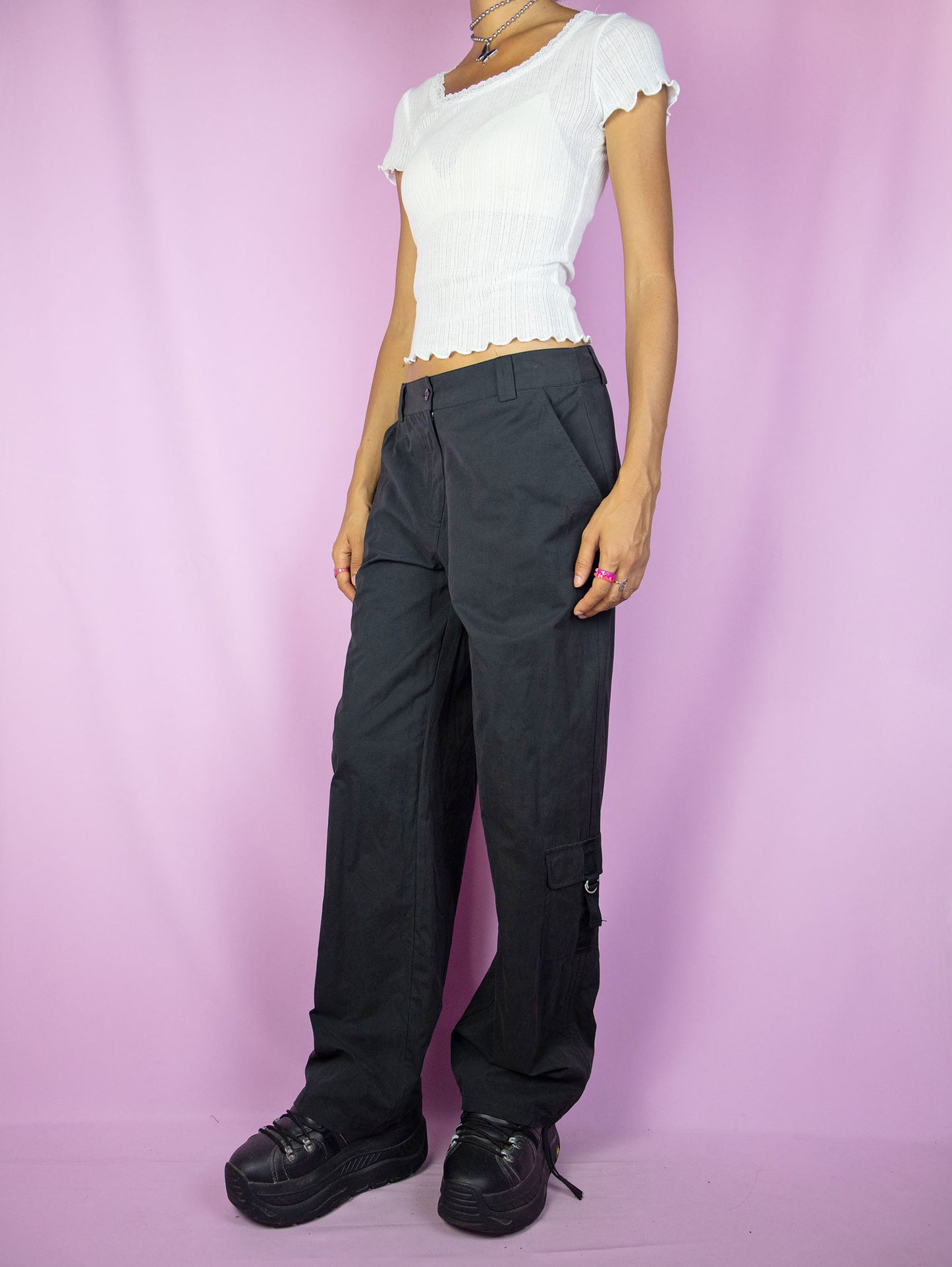 The Y2K Black Cargo Pants are vintage mid-rise wide pants with pockets and a front zipper closure. Cyber grunge 2000s utility trousers.