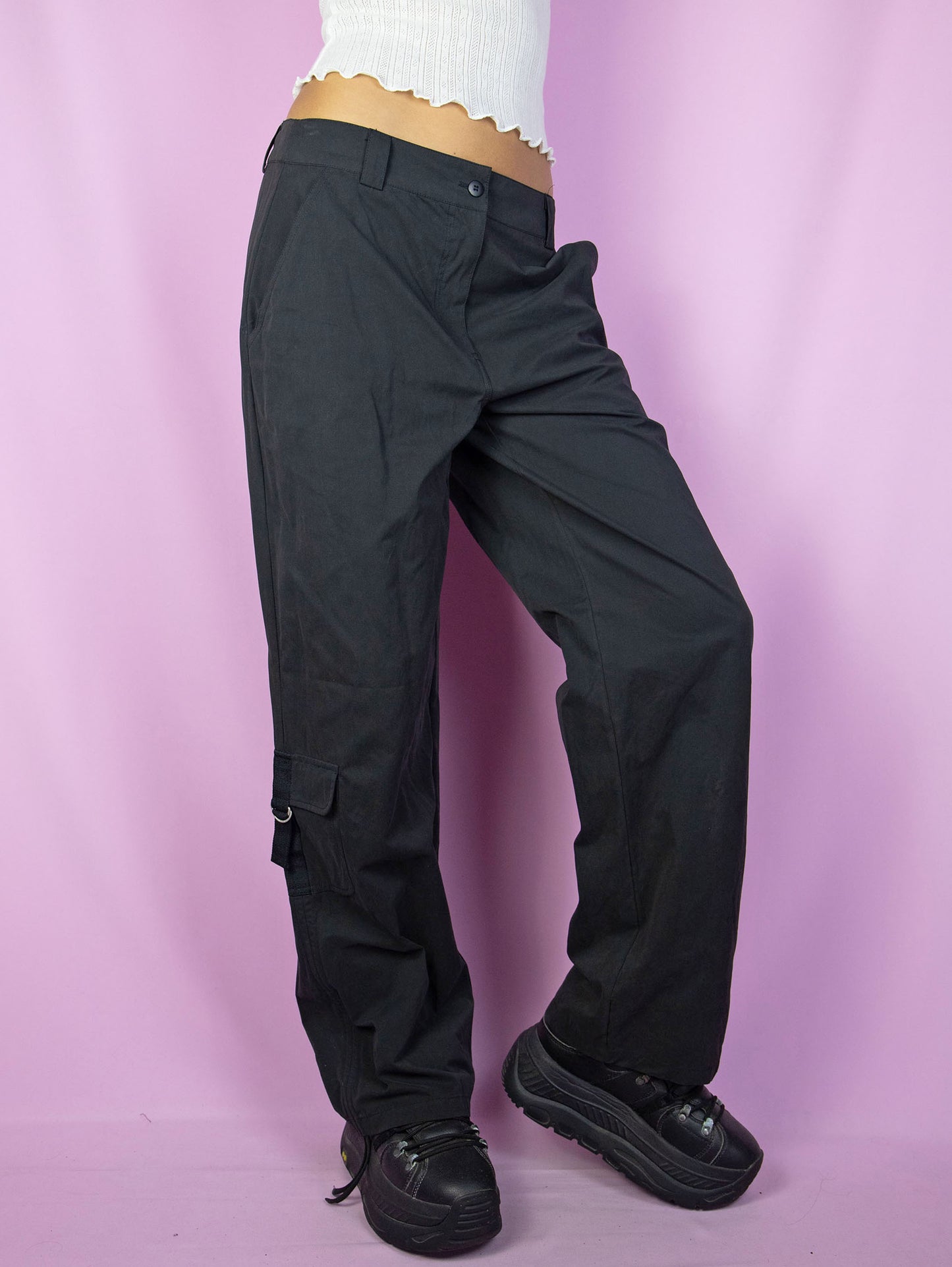 The Y2K Black Cargo Pants are vintage mid-rise wide pants with pockets and a front zipper closure. Cyber grunge 2000s utility trousers.