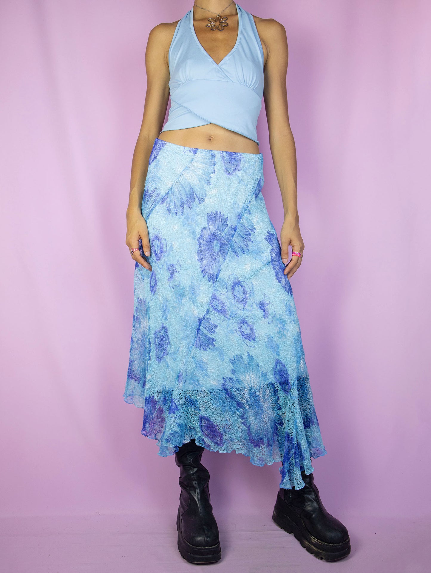 The Y2K Blue Mesh Midi Skirt is a vintage 2000s piece featuring a floral print, an asymmetrical hem, an elastic waistband, and a lightweight semi-sheer overlay. Perfect for adding a whimsical touch to your spring or summer wardrobe.