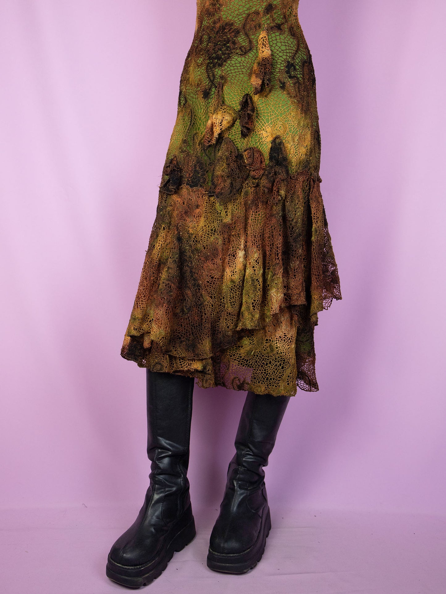 The Y2K Fairy Brown Midi Dress is a vintage sleeveless crochet-style mesh dress with a tie-dye pattern and a green lining. It features a layered ruffled hem, and a charming asymmetric design. Romantic avant-garde 2000s evening party dress.