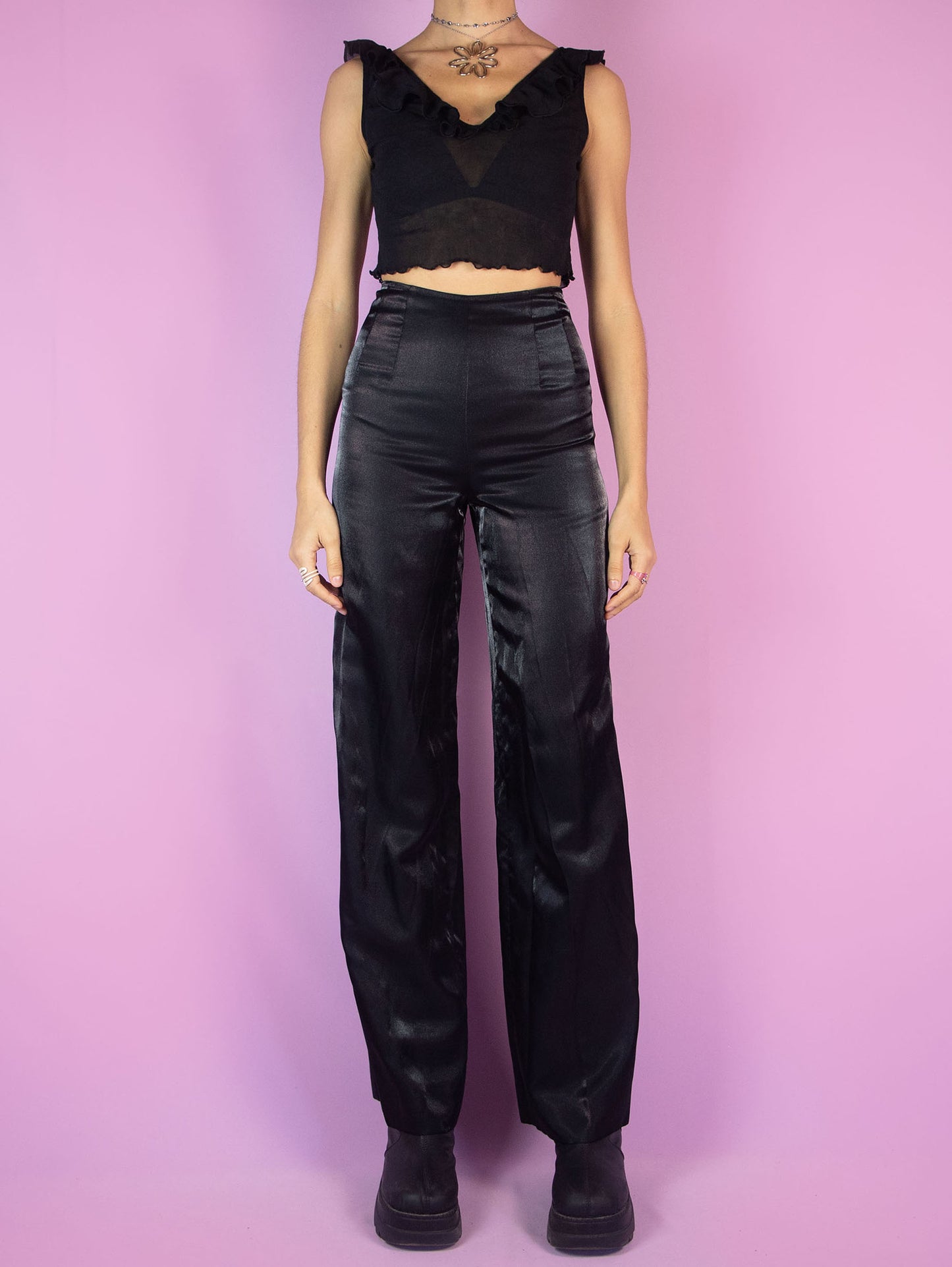 The Vintage 90s Black Wide Pants are high-waisted trousers featuring a wide-leg silhouette. They have a side zipper closure and delicate pleats at the waist. Crafted from an iridescent, satin-like fabric, they are perfect for evening outings or formal occasions.