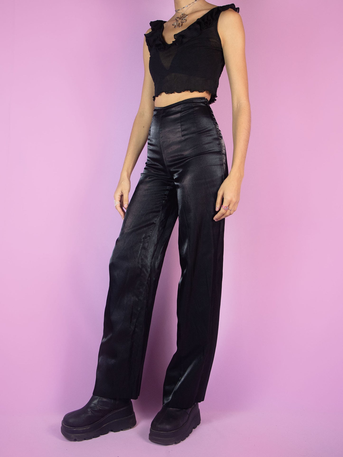 The Vintage 90s Black Wide Pants are high-waisted trousers featuring a wide-leg silhouette. They have a side zipper closure and delicate pleats at the waist. Crafted from an iridescent, satin-like fabric, they are perfect for evening outings or formal occasions.