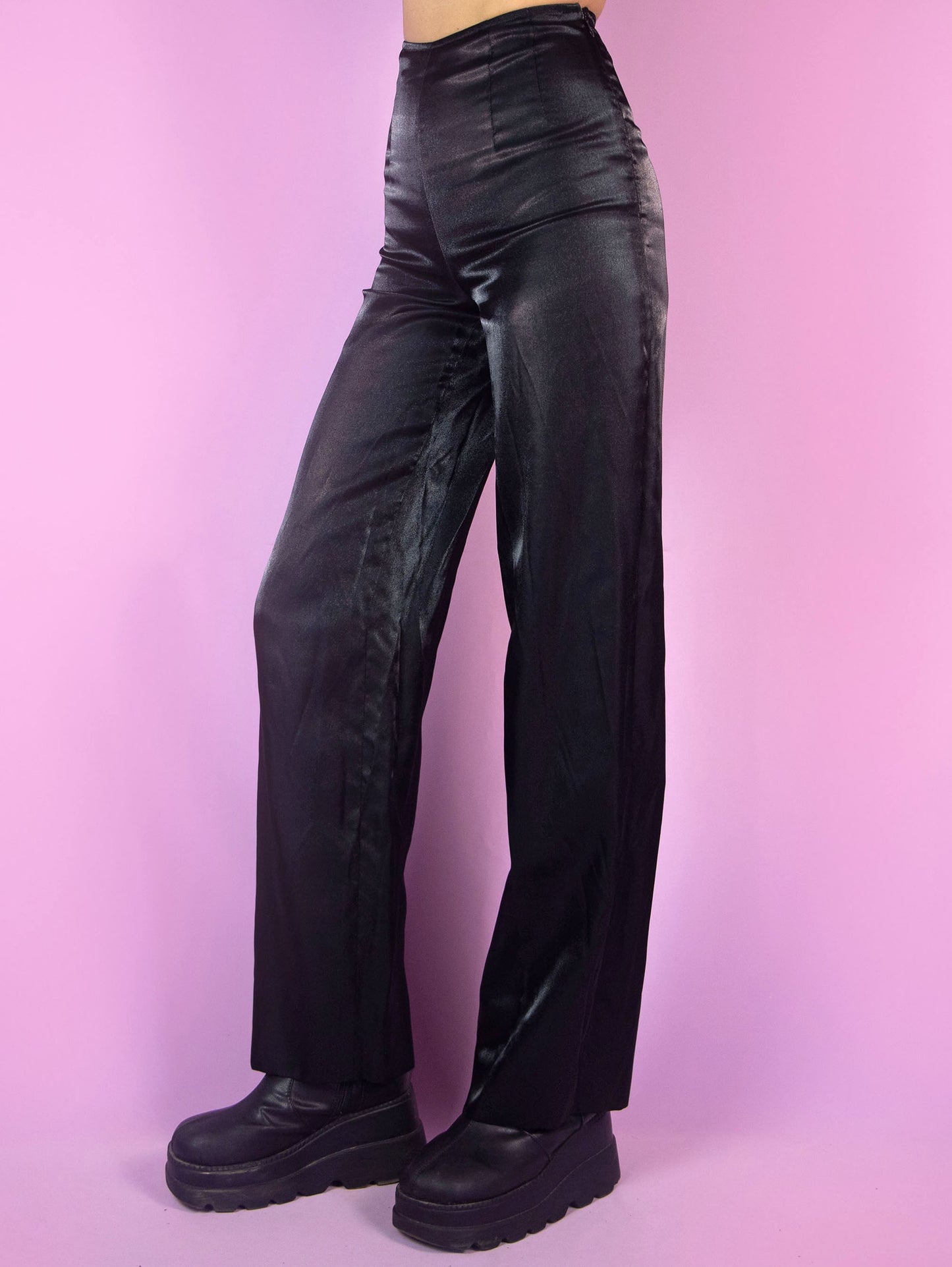 The Vintage 90s Black Wide Pants are high-waisted trousers featuring a wide-leg silhouette. They have a side zipper closure and delicate pleats at the waist. Crafted from an iridescent, satin-like fabric, they are perfect for evening outings or formal occasions.