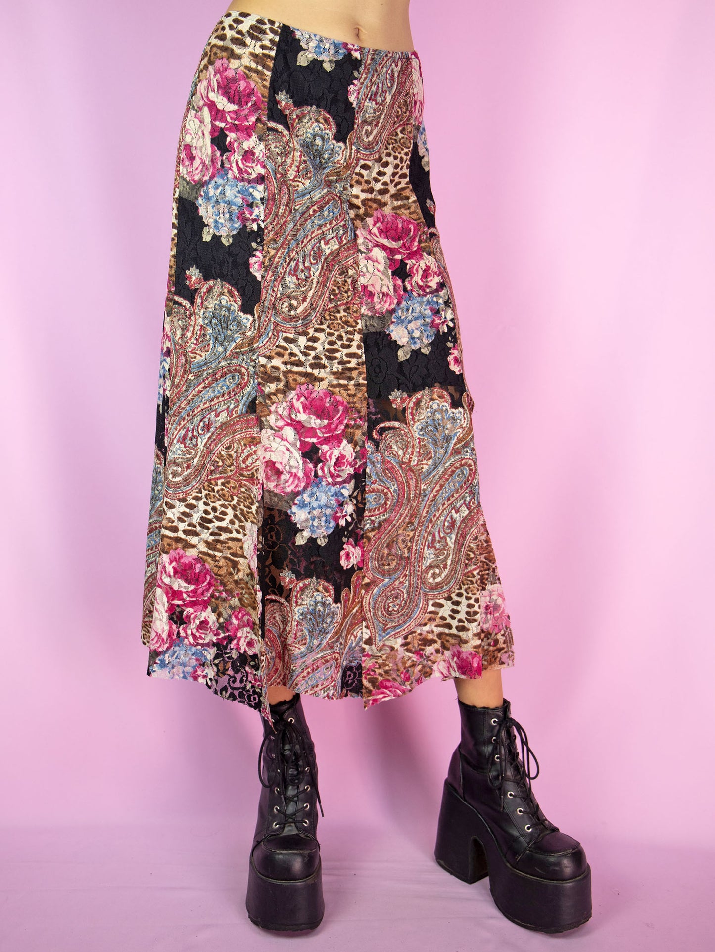 The Y2K Lace Mesh Midi Skirt is a vintage 2000s skirt featuring an abstract floral and paisley patchwork design. Crafted from semi-sheer mesh fabric with lace details, it has an elastic waist and a spliced hem. This skirt is perfect for summer parties and boho-inspired outfits.
