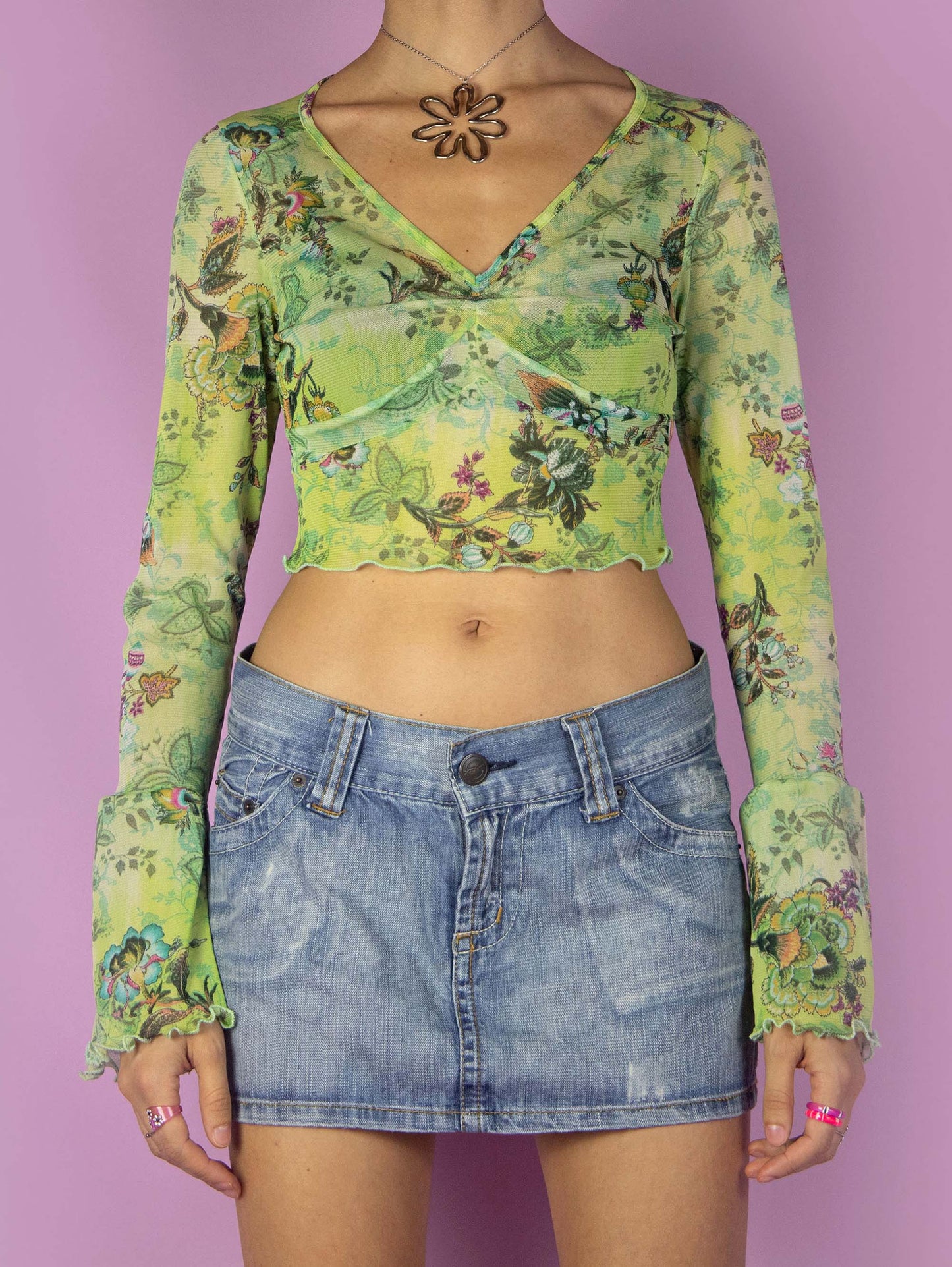 The Y2K Graphic Mesh Crop Top is a vintage bell-sleeved semi-sheer green shirt with an abstract floral pattern and a lettuce hem. Cyber fairy grunge 2000s printed top.
