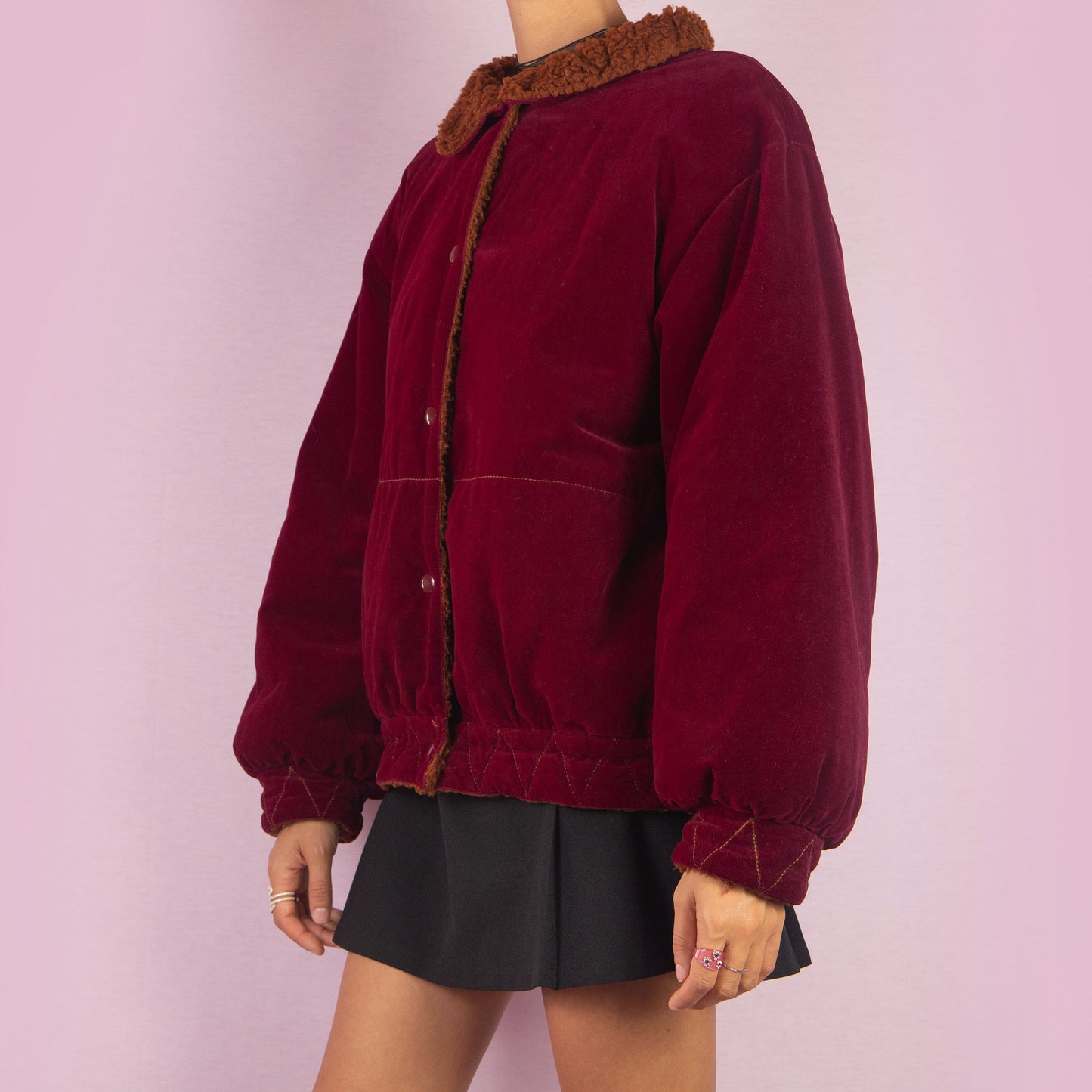 The Vintage 90s Red Velvet Bomber Jacket is a striking piece with a deep red velvet exterior featuring a contrasting brown faux shearling collar and inner lining. It includes snap button closures. Perfect for casual winter days or adding a bold touch to any outfit. Made in Italy.