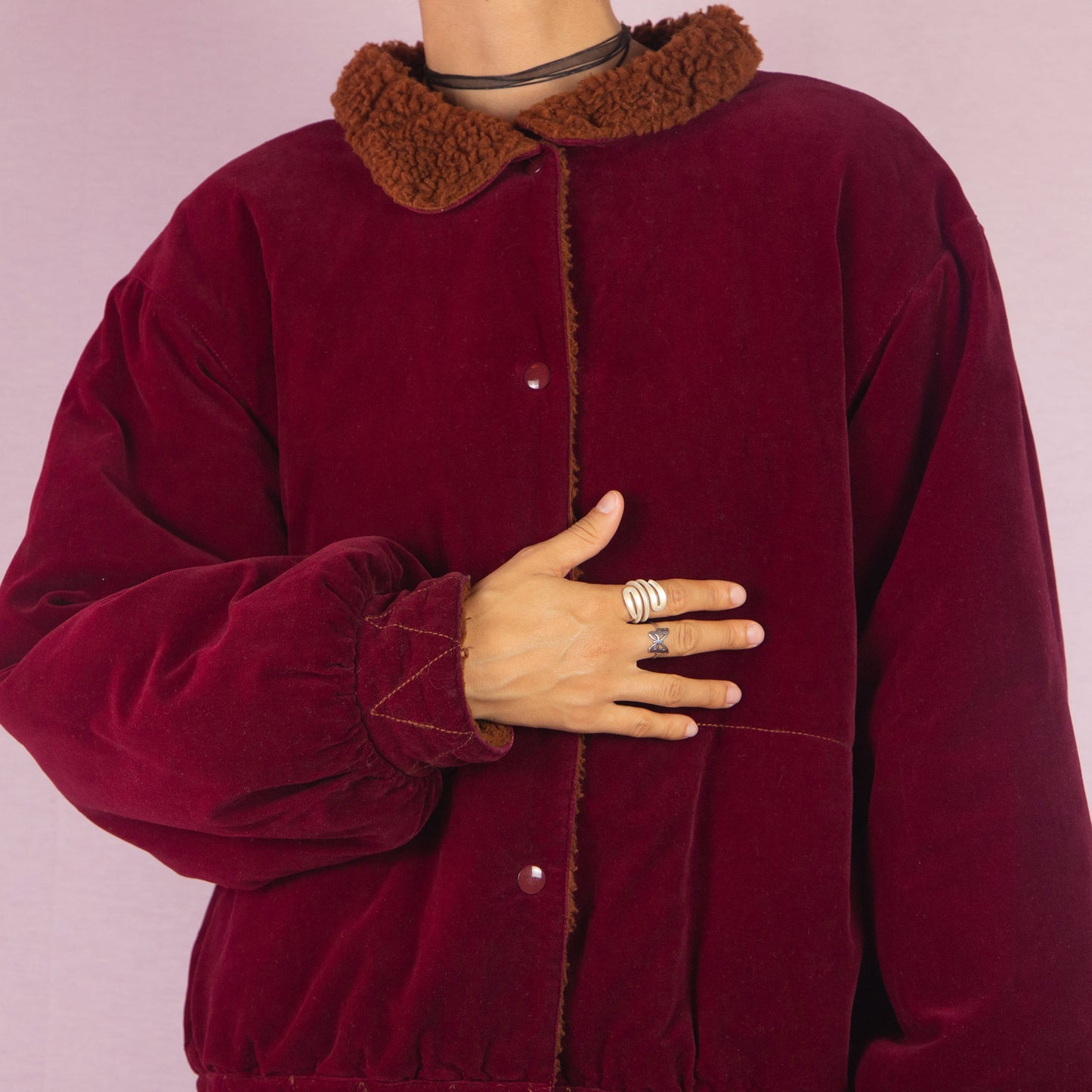 The Vintage 90s Red Velvet Bomber Jacket is a striking piece with a deep red velvet exterior featuring a contrasting brown faux shearling collar and inner lining. It includes snap button closures. Perfect for casual winter days or adding a bold touch to any outfit. Made in Italy.