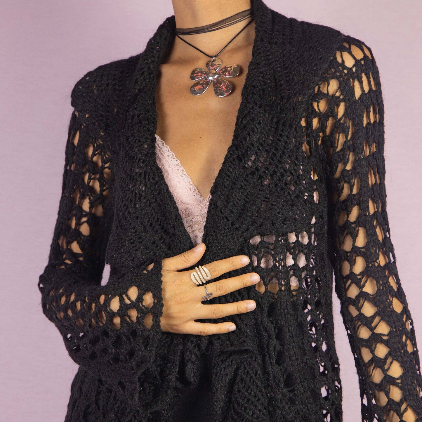 The Y2K Black Ruffle Crochet Cardigan is a vintage 2000s piece featuring an open-knit crochet design with an open front, flared sleeves, and a flowy ruffled hem. This lightweight cardigan is perfect for layering, adding a boho touch to any casual or party outfit.