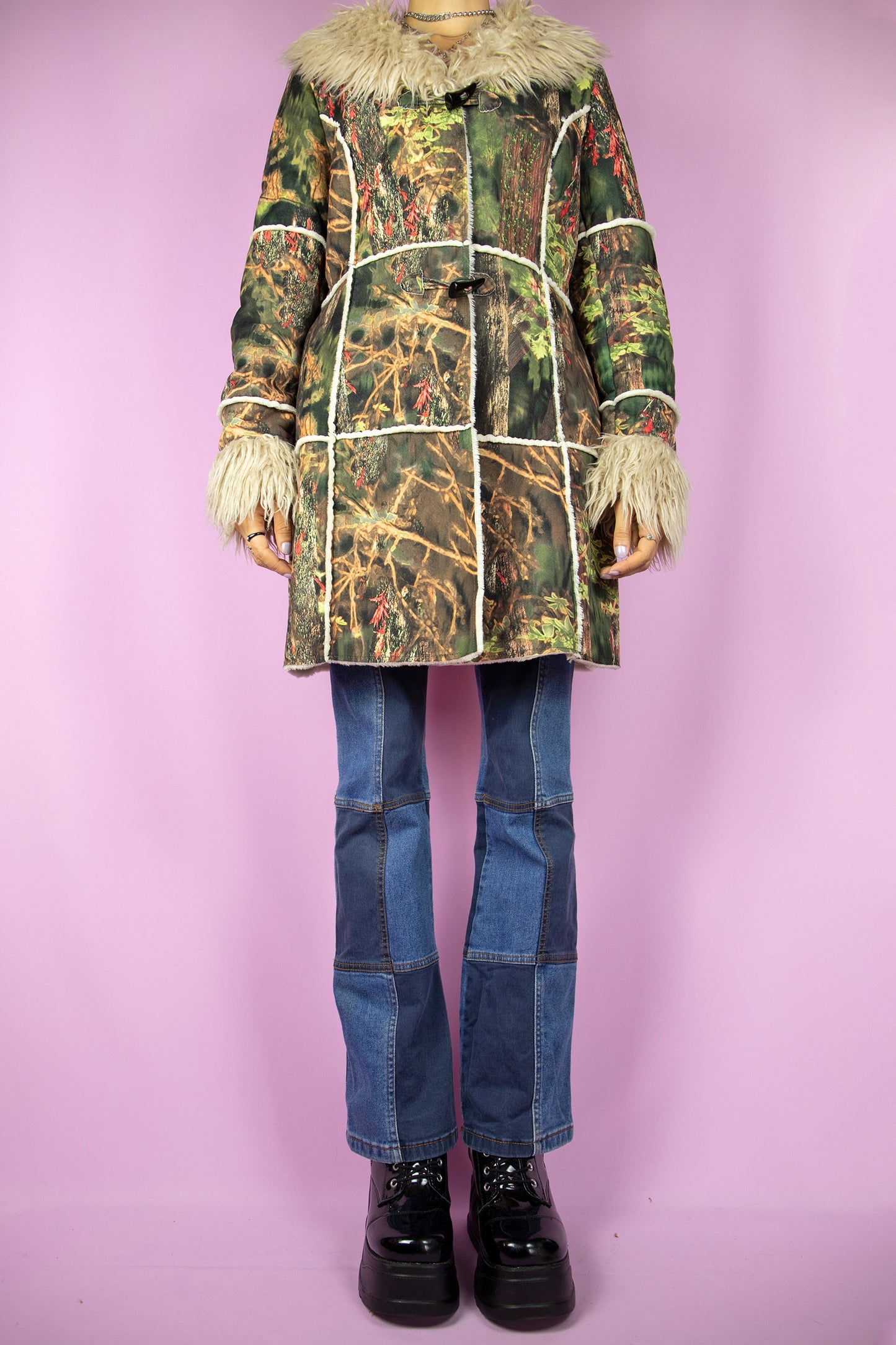 The Y2K Green Penny Lane Coat is a vintage 2000s jacket featuring an abstract forest graphic print, beige faux fur collar and cuffs, pockets, and a toggle closure. Perfect as a statement piece for winter outfits.