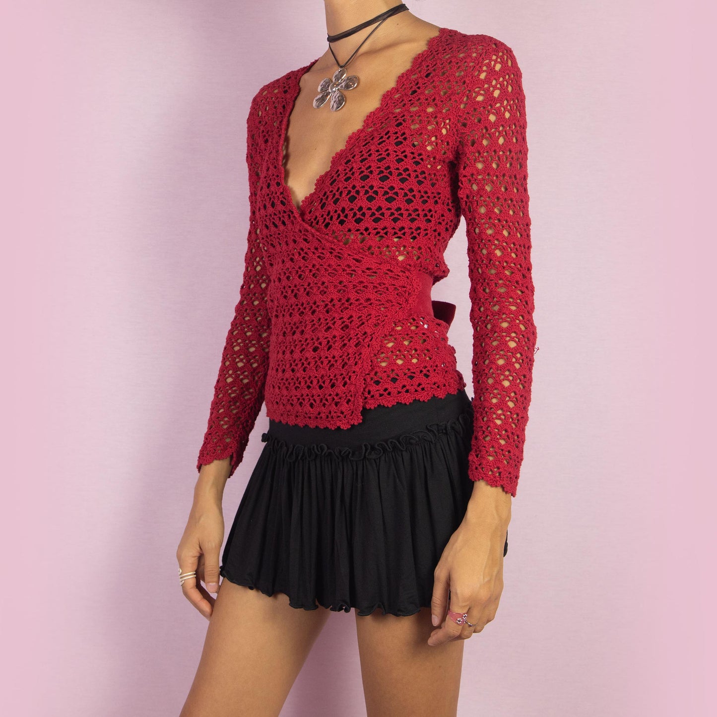 The Y2K Red Crochet Wrap Cardigan is a vintage 2000s piece featuring a romantic deep V-neckline with an intricate open-knit design. Its wrap style and tie closure at the back form a stylish bow, creating a flattering silhouette. Perfect for layering in spring and summer.