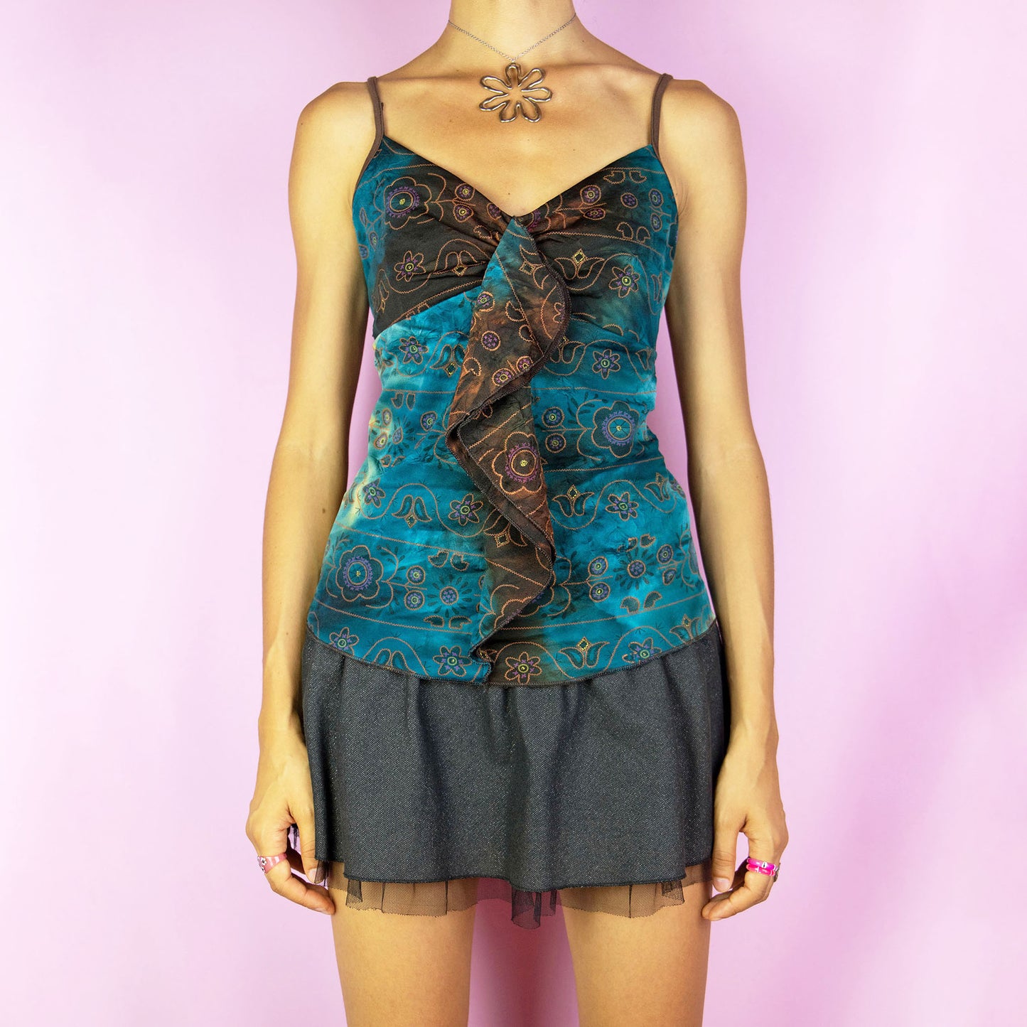 The Y2K Printed Ruffle Cami Top is a vintage 2000s top featuring a ruffled design along the neckline and straps. This top showcases a tie-dye and floral pattern, adding a boho vibe that is ideal for summer.
