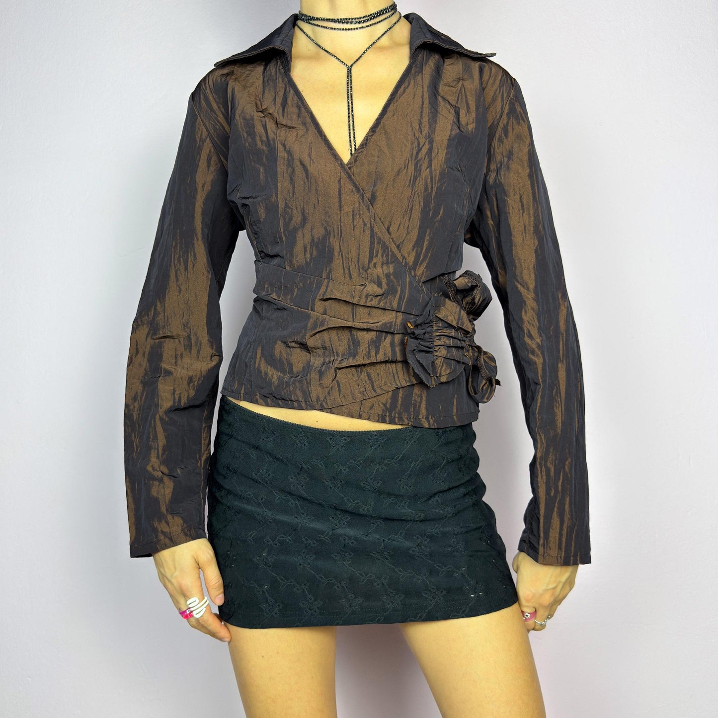 The Vintage 90s Brown Wrap Tie Blouse features a textured, crinkled fabric with a subtle iridescent finish, a flattering wrap design with a tie at the side. The deep brown tone adds versatility, while the structured collar. adult world shop