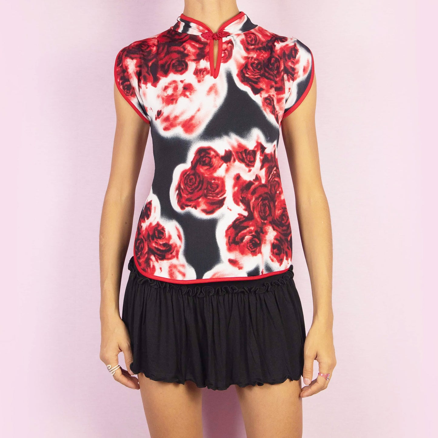 The Vintage 90s Rose Print Top is a striking piece featuring a bold red and black rose print and cap sleeves. The design is enhanced by a Qipao-inspired high collar with a decorative frog closure and a keyhole detail. Perfect for casual or evening looks.