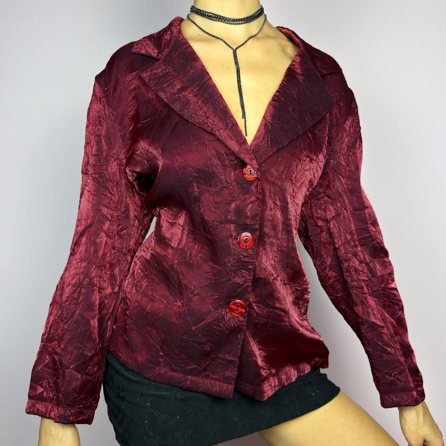 The Vintage 90s Red Iridescent Jacket is a striking and glamorous piece featuring a textured, crinkled design with a luxurious, iridescent sheen. This button-up jacket showcases a deep red tone, wide lapels, and bold red buttons. adult world shop