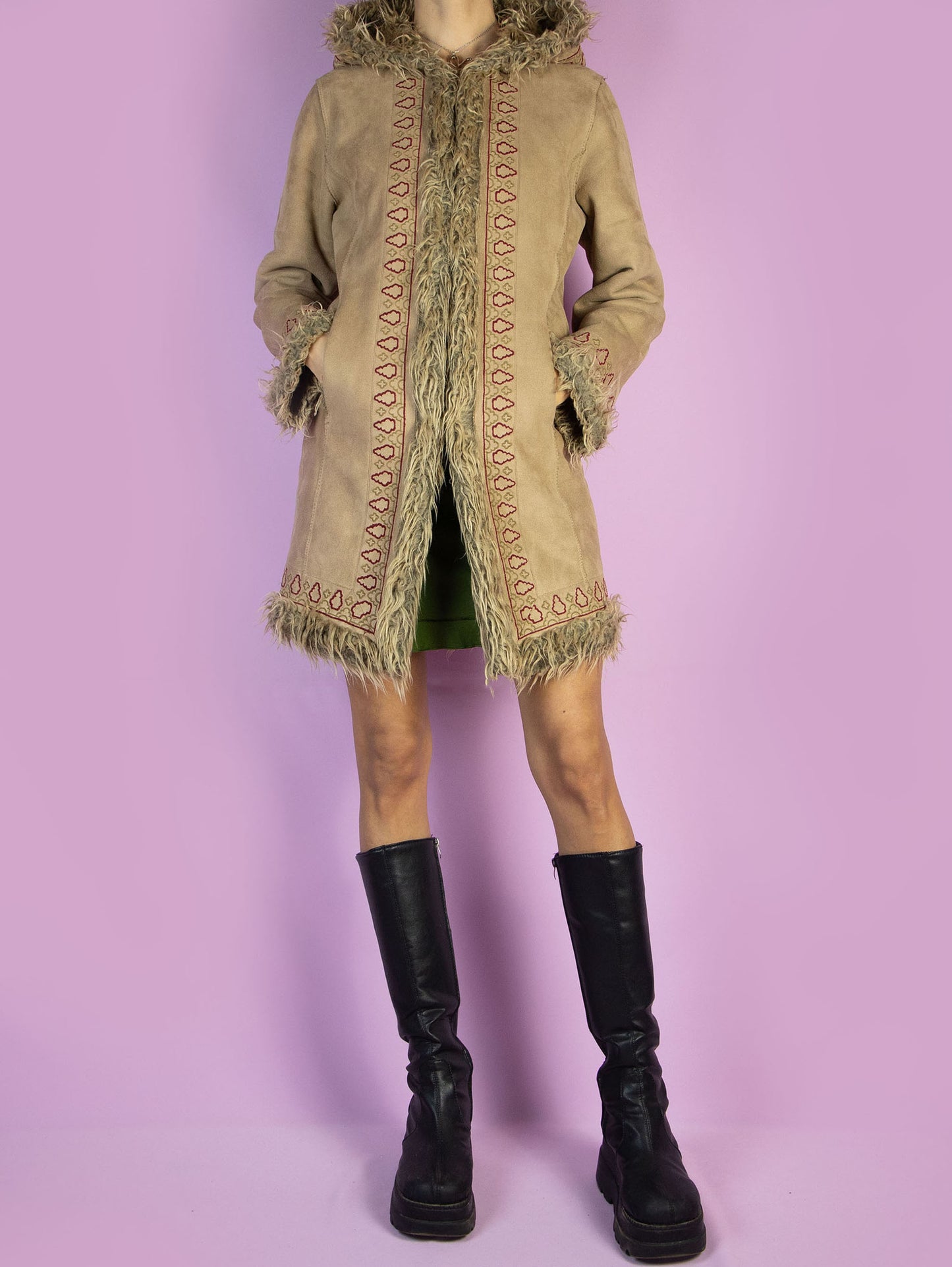 The Y2K Beige Afghan Hooded Coat is a vintage 2000s Penny Lane-style winter jacket crafted from light brown faux suede with shaggy faux fur trim on the hood, cuffs, and interior. Featuring intricate embroidered detailing, front pockets, and hook-and-eye closures, this warm mid-length coat brings boho drama and retro charm to cold-weather outfits. A standout piece for winter layering with a romantic, nostalgic edge.