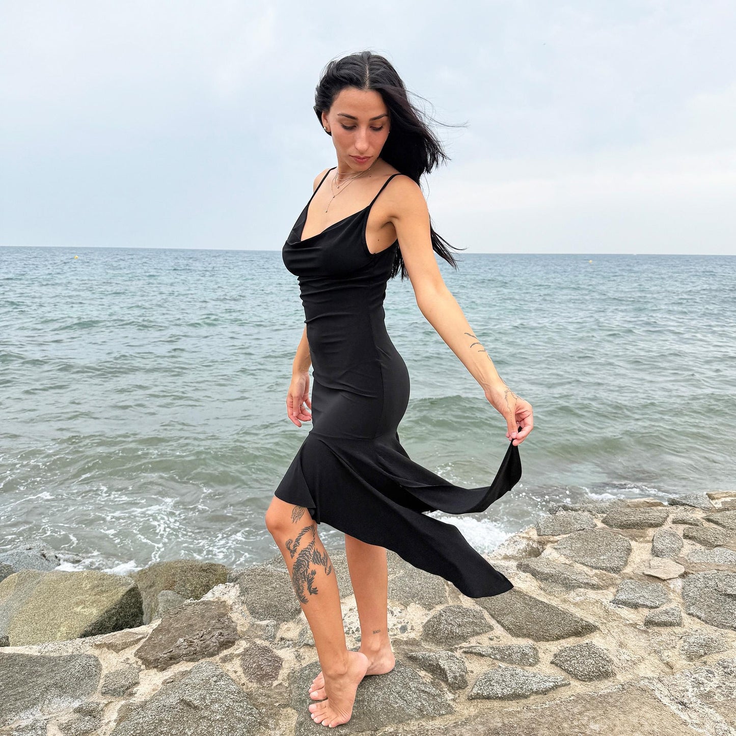 This black vintage 2000s dress features a plunging cowl neckline, and an asymmetrical ruffle hem that flutters with movement. Designed in a flattering cocktail length with a body-hugging silhouette, it’s perfect for summer nights, beach parties, or alt club looks. French-made for a dramatic, femme-fatale feel. An iconic Y2K editorial piece for minimalist seduction. Made from a polyester stretch blend. Great vintage condition.