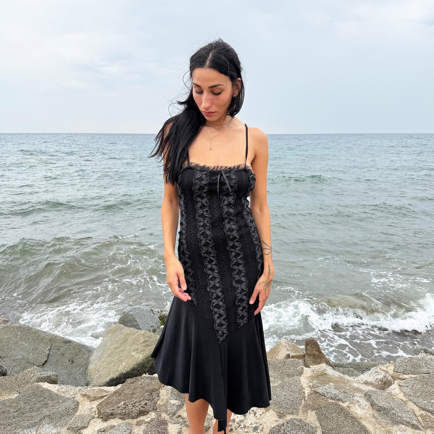 This vintage 2000s black midi dress features an asymmetrical handkerchief hem with whimsical flow and delicate mesh panel details through the bodice. Crafted in France from a stretchy polyester blend, it hugs the figure while allowing movement. A romantic dark piece with fairy, witchy, and night-party energy—perfect for Y2K alternative styling. Made from polyester stretch blend. Excellent vintage condition.