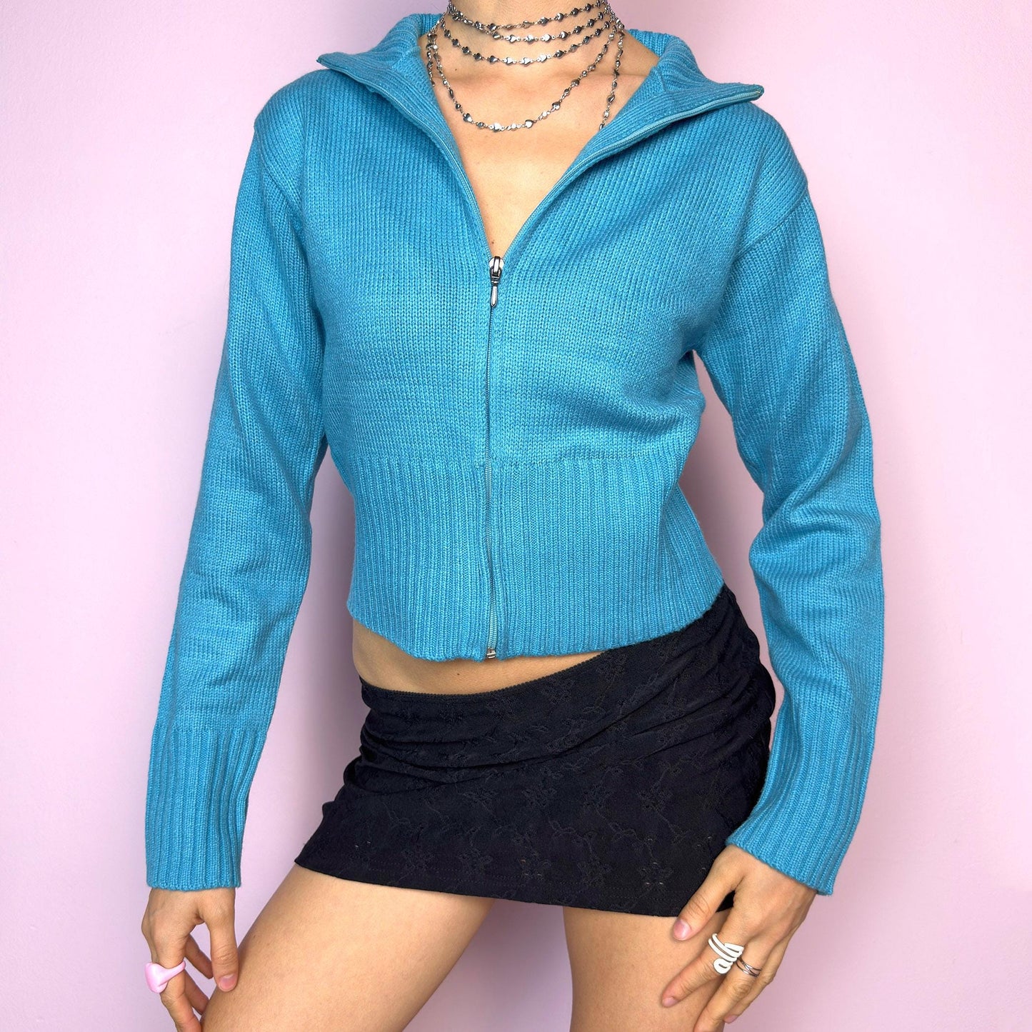 The Y2K Blue Zip Cardigan is a vintage 2000s cropped zip-up knit featuring a vibrant aqua blue tone, a flattering fitted silhouette, a wide collar, and ribbed hem and cuffs. Ideal for layering or adding a pop of color to your casual autumn outfits. Excellent vintage condition. adult world shop
