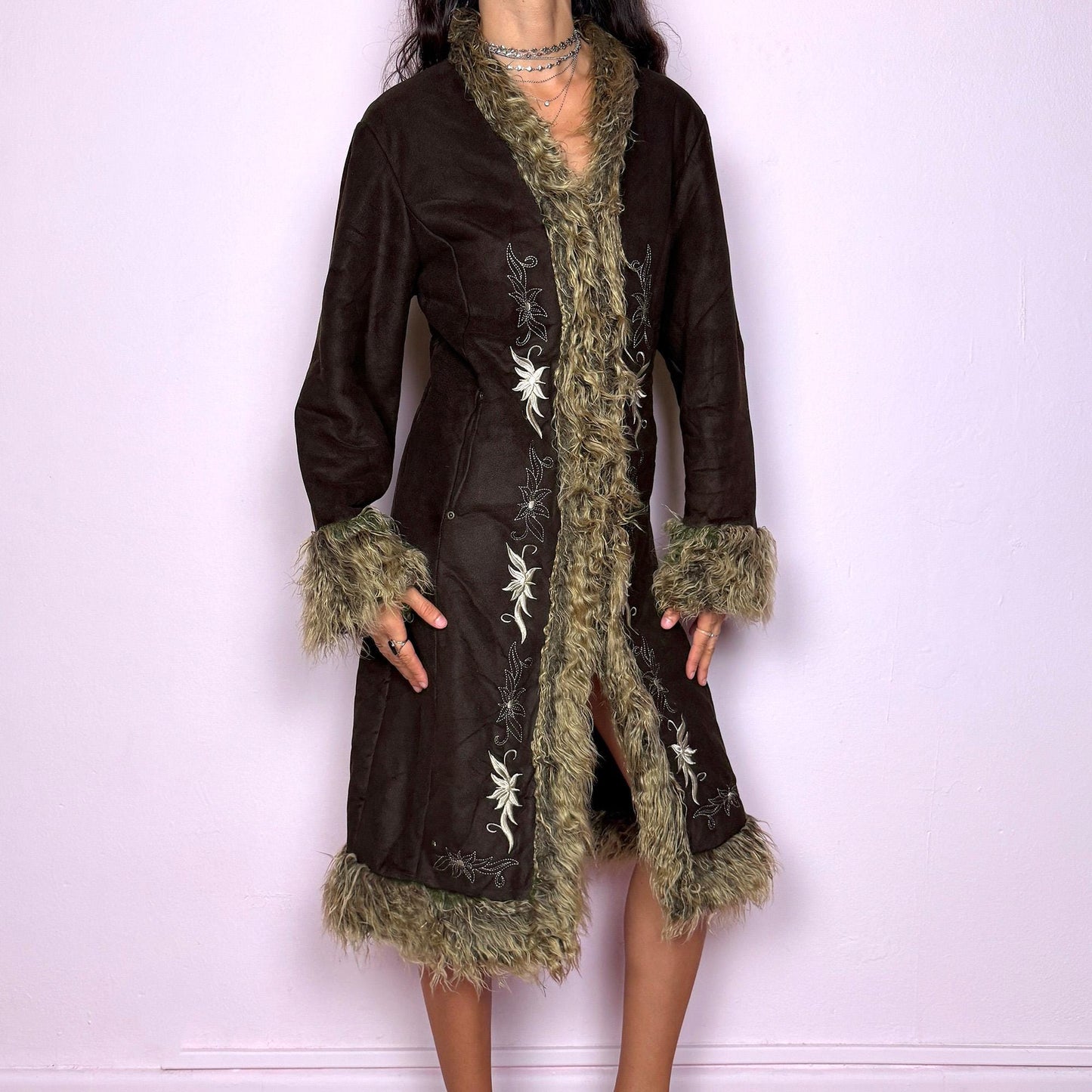 This vintage 2000s dark brown Penny Lane coat features beige faux fur trim at the collar, cuffs, and hem, with intricate floral embroidery along the front. Crafted from soft faux suede with pockets and dual snap-and-hook closure, it embodies the whimsical 70s Afghan-inspired Y2K aesthetic. Warm and romantic—perfect for fairycore, boho, and forest muse styling. Made from polyester faux suede and faux fur. Great vintage condition.