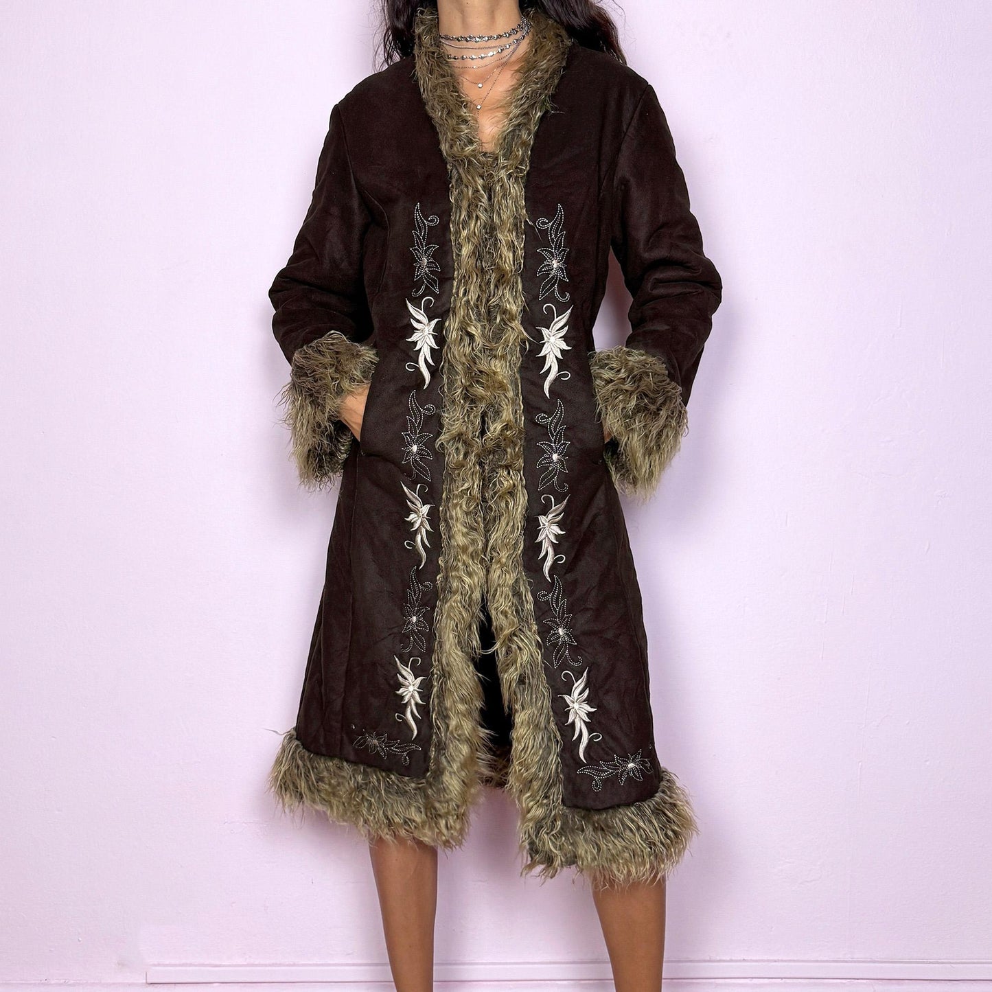 This vintage 2000s dark brown Penny Lane coat features beige faux fur trim at the collar, cuffs, and hem, with intricate floral embroidery along the front. Crafted from soft faux suede with pockets and dual snap-and-hook closure, it embodies the whimsical 70s Afghan-inspired Y2K aesthetic. Warm and romantic—perfect for fairycore, boho, and forest muse styling. Made from polyester faux suede and faux fur. Great vintage condition.