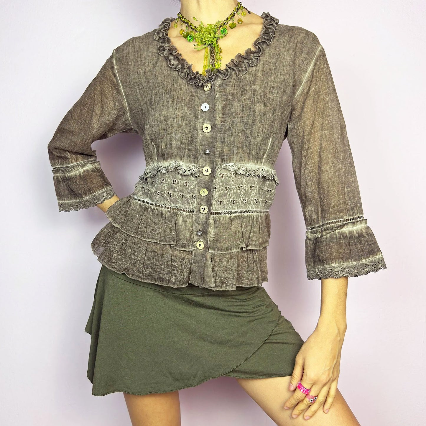 The Y2K Brown Ruffle Frill Blouse is a vintage 2000s piece featuring a faded brown wash with delicate lace trims and tiered ruffle details for a romantic, fairy-grunge aesthetic. Designed with a button-up front, 3/4 bell sleeves, this blouse blends cottagecore and bohemian elements effortlessly. The soft, lightweight fabric makes it perfect for dreamy summer outfits.