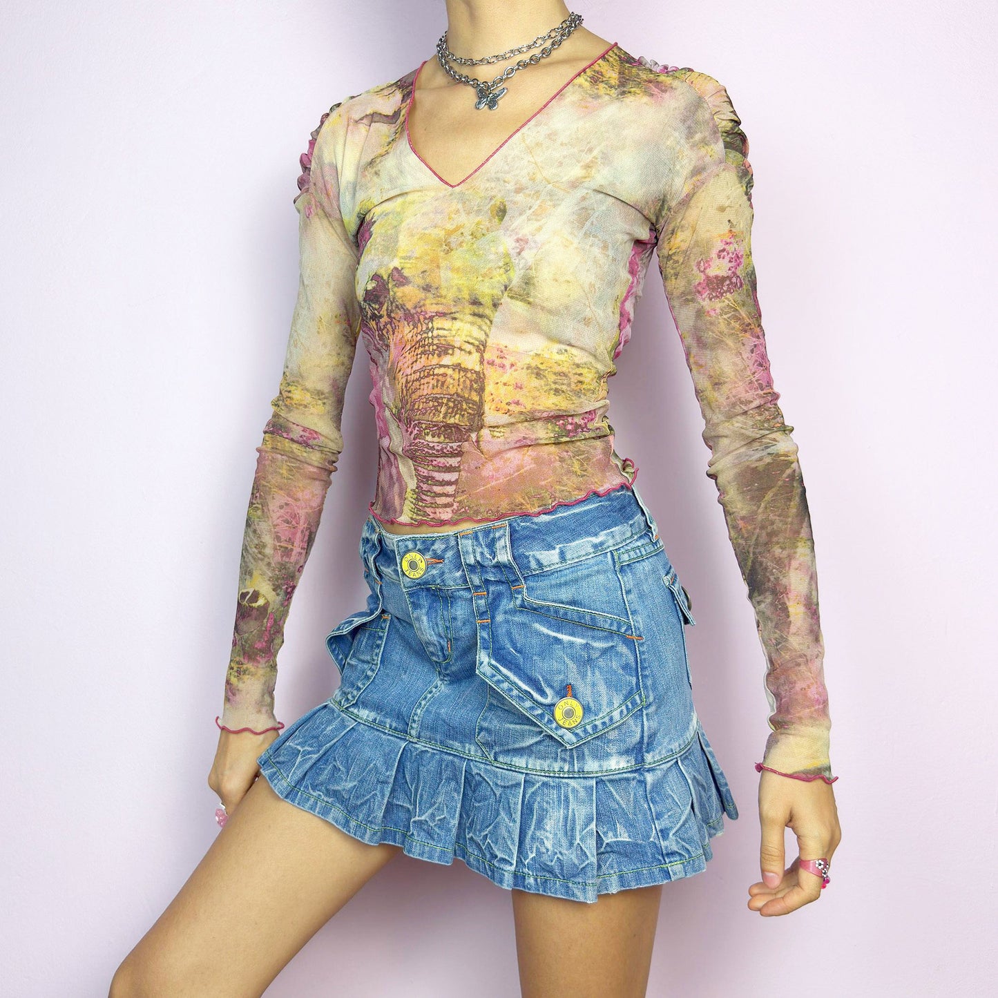 The Y2K Pleated Mini Denim Skirt is a vintage 2000s piece featuring a pleated hem and cargo-style pockets with button details for a playful, utilitarian touch. Crafted from washed blue denim with contrast stitching, this low-rise mini has a button and zipper closure. Perfect for casual, streetwear, or festival looks.