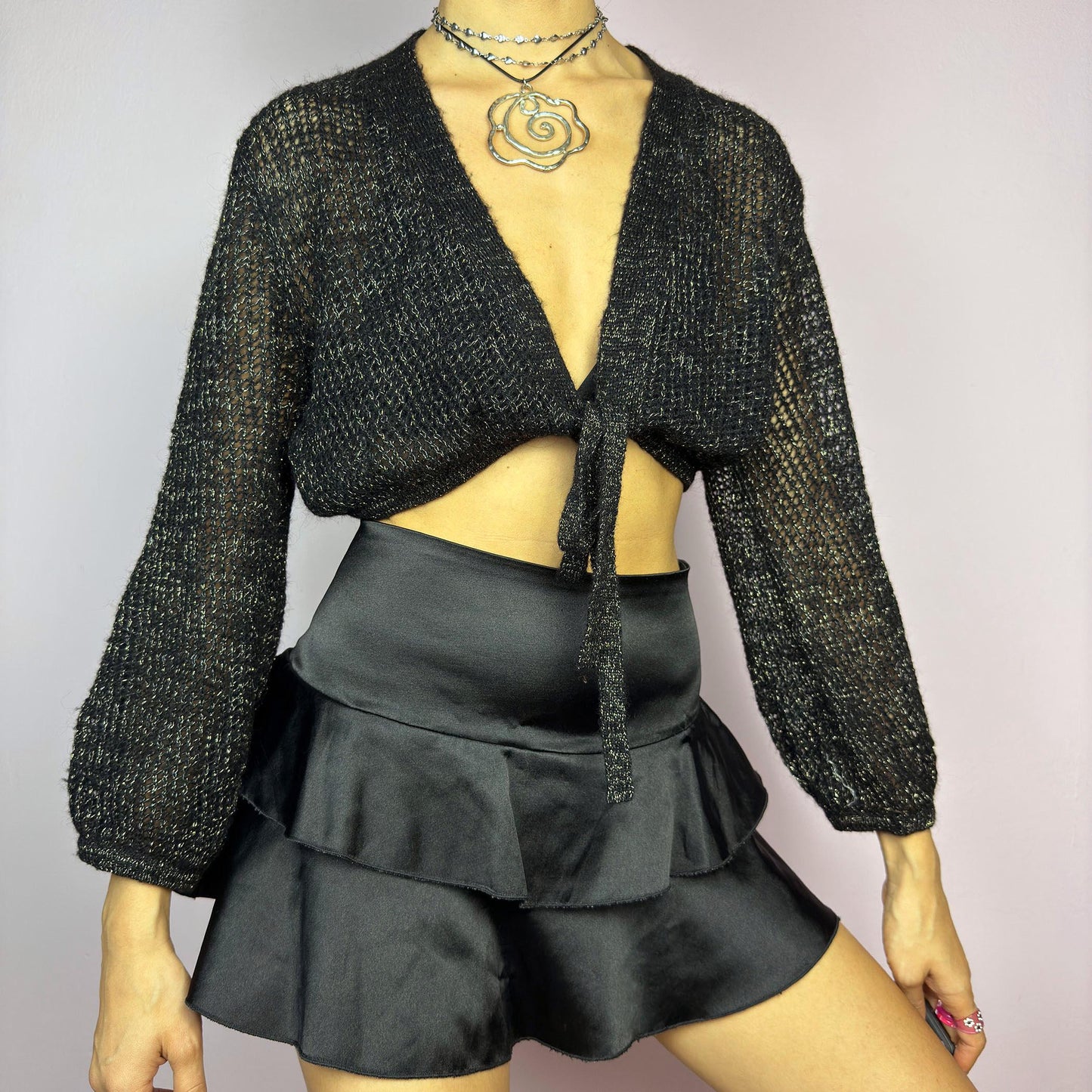 This Y2K Black Tie Front Cardigan is a vintage 2000s piece featuring a lightweight open-knit design with a subtle metallic shimmer, a cropped fit and long sleeves. Perfect for layering and ideal for night-out or casual outfits