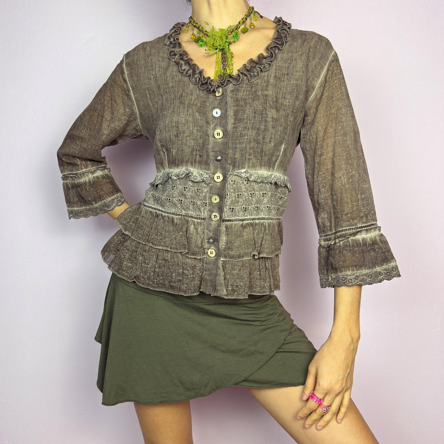 The Y2K Brown Ruffle Frill Blouse is a vintage 2000s piece featuring a faded brown wash with delicate lace trims and tiered ruffle details for a romantic, fairy-grunge aesthetic. Designed with a button-up front, 3/4 bell sleeves, this blouse blends cottagecore and bohemian elements effortlessly. The soft, lightweight fabric makes it perfect for dreamy summer outfits. adult world shop
