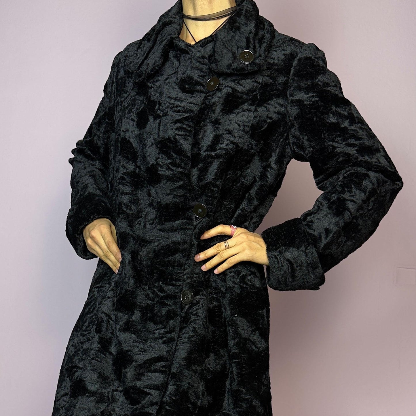 The Vintage 90s Black Faux Fur Long Coat features a plush faux fur exterior for a cozy feel. Designed with a button front closure, it includes long sleeves and pockets. Its longline silhouette makes it a chic and warm choice for winter evenings