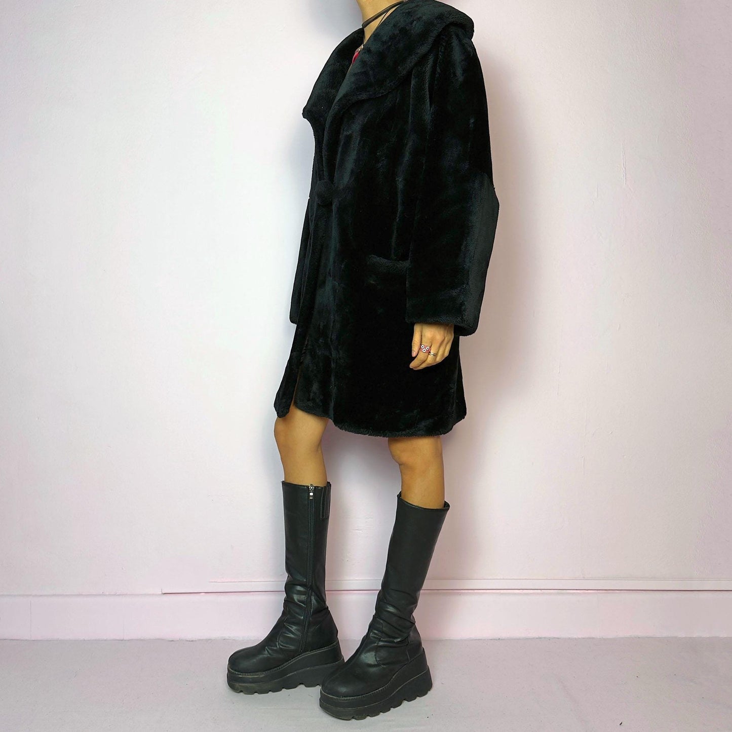 The Vintage 90s Black Faux Fur Coat showcases a faux fur material for a sophisticated and cozy winter style. It features a plush oversized collar, a chic fabric-covered button closure, and pockets. Perfect for winter outings or evening events.