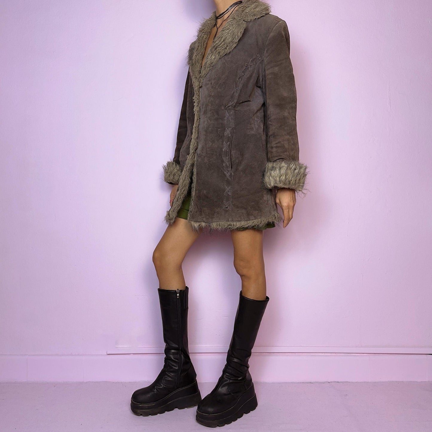 The Vintage 90s Brown Suede Penny Lane Coat showcases a brown leather suede finish paired with soft faux fur trims along the collar, cuffs, and hemline. This jacket features button closures and intricate stitch details. Its timeless design