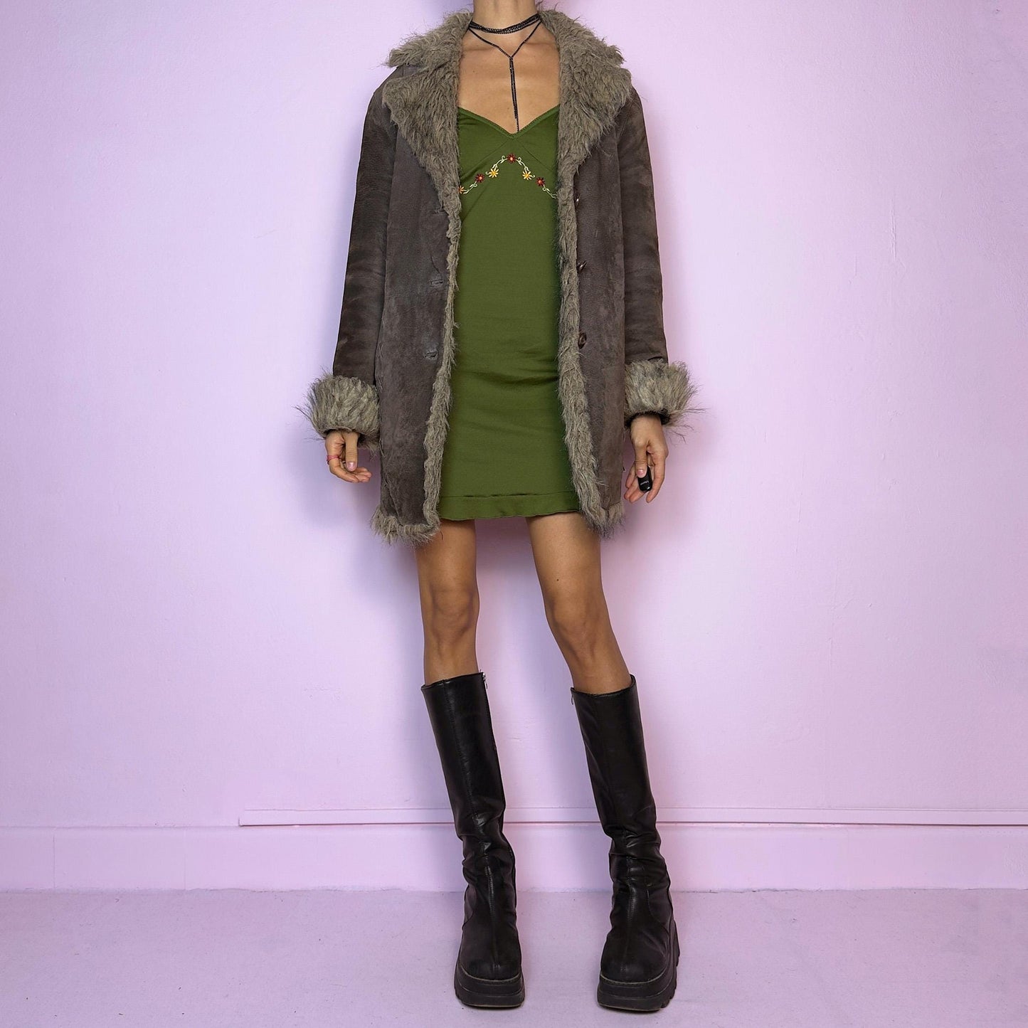The Vintage 90s Brown Suede Penny Lane Coat showcases a brown leather suede finish paired with soft faux fur trims along the collar, cuffs, and hemline. This jacket features button closures and intricate stitch details. Its timeless design