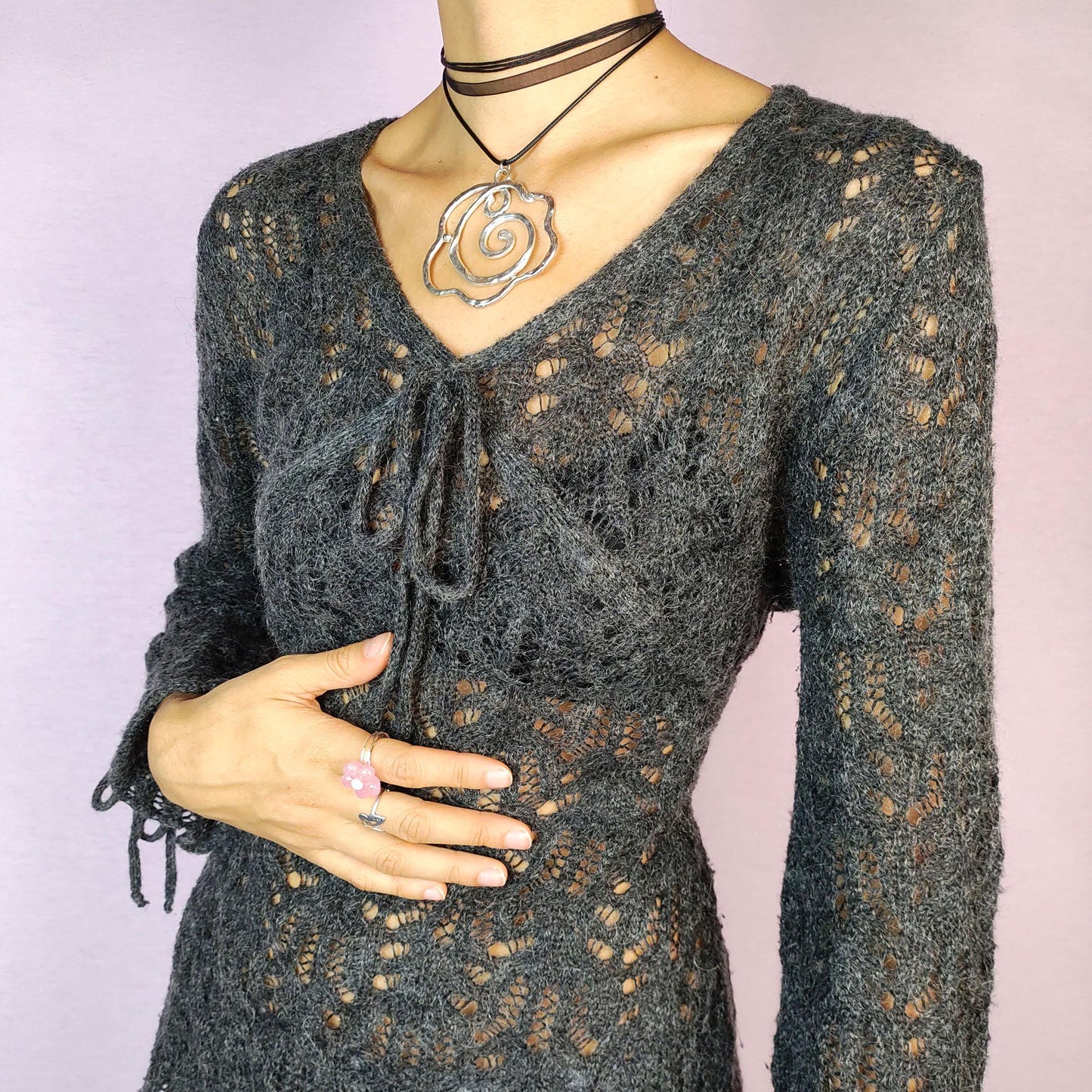 The Y2K Gray Sheer Sweater is a vintage 2000s pullover featuring a delicate knit pattern with semi-sheer details, offering a lightweight yet cozy feel. Designed with three quarter sleeves and a tie detail at the neckline, this sweater