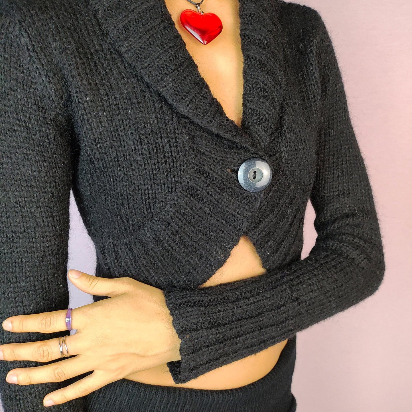 The Y2K Black Cropped Bolero Cardigan is a vintage 2000s piece featuring a chic single-button front closure and a shawl collar. This bolero-style cardigan is crafted from a soft knit fabric and the cropped silhouette makes it perfect for layering.